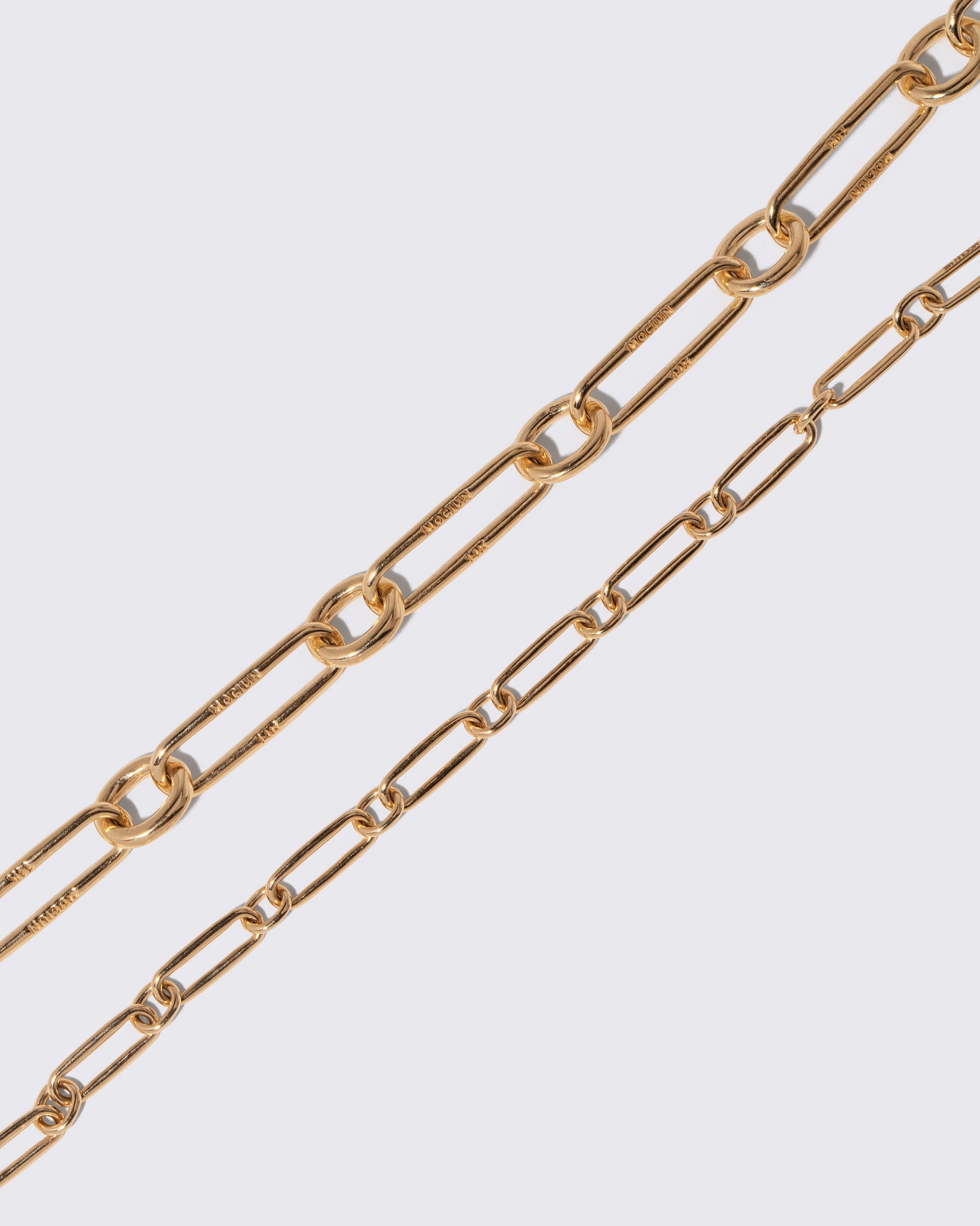 Closeup details of the Gold Link Bracelet and Petite Link Bracelet on light color background.