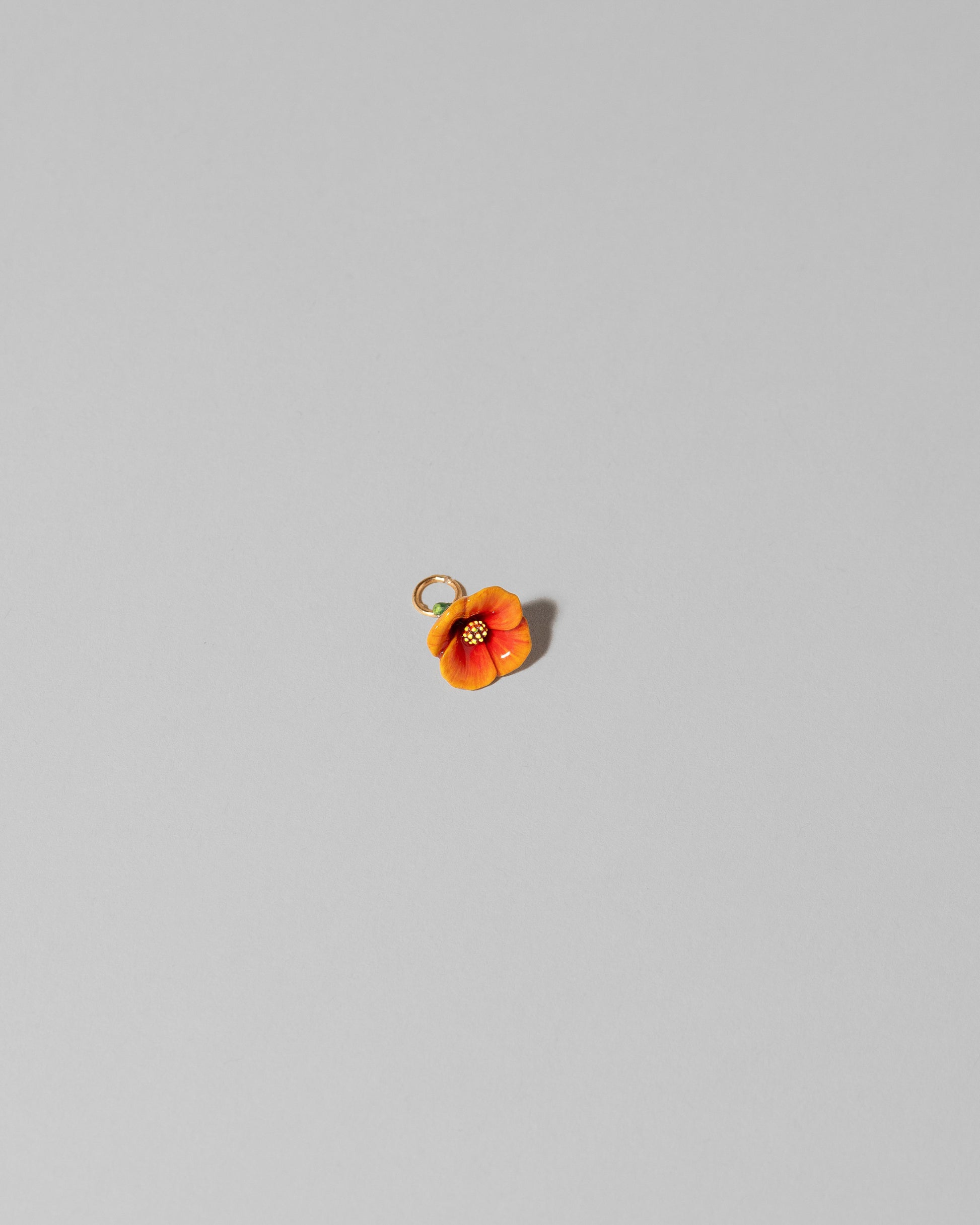 Closeup details of the California Poppy Charm on light color background.