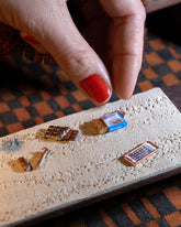 Styled image of the Chocolate Bar Charm, with the Joint Charm, Dirty Martini Charm and Instant Ramen Charm.