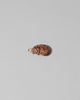 View from the side of the Curled-Up Cat Charm on light color background.