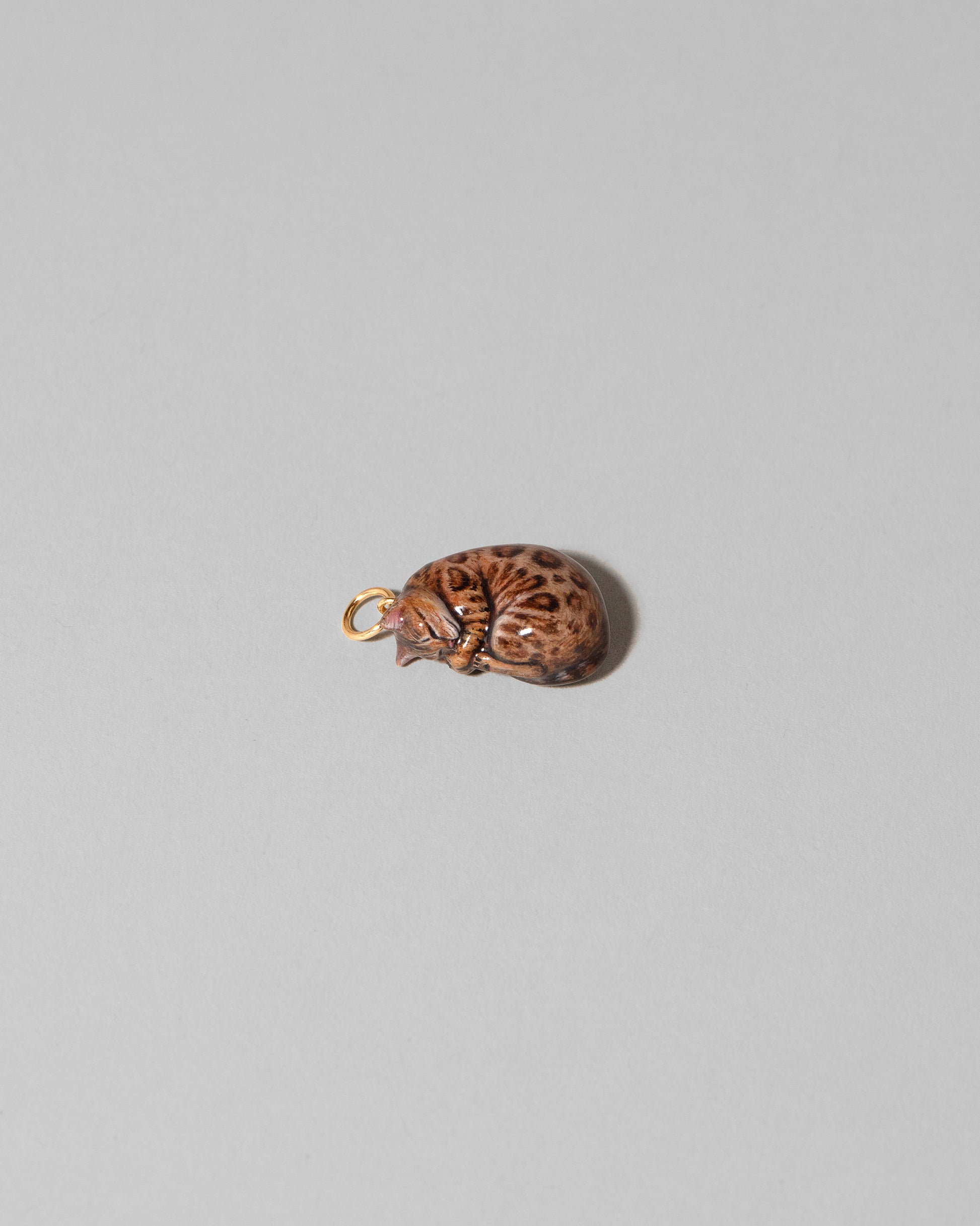 View from the side of the Curled-Up Cat Charm on light color background.