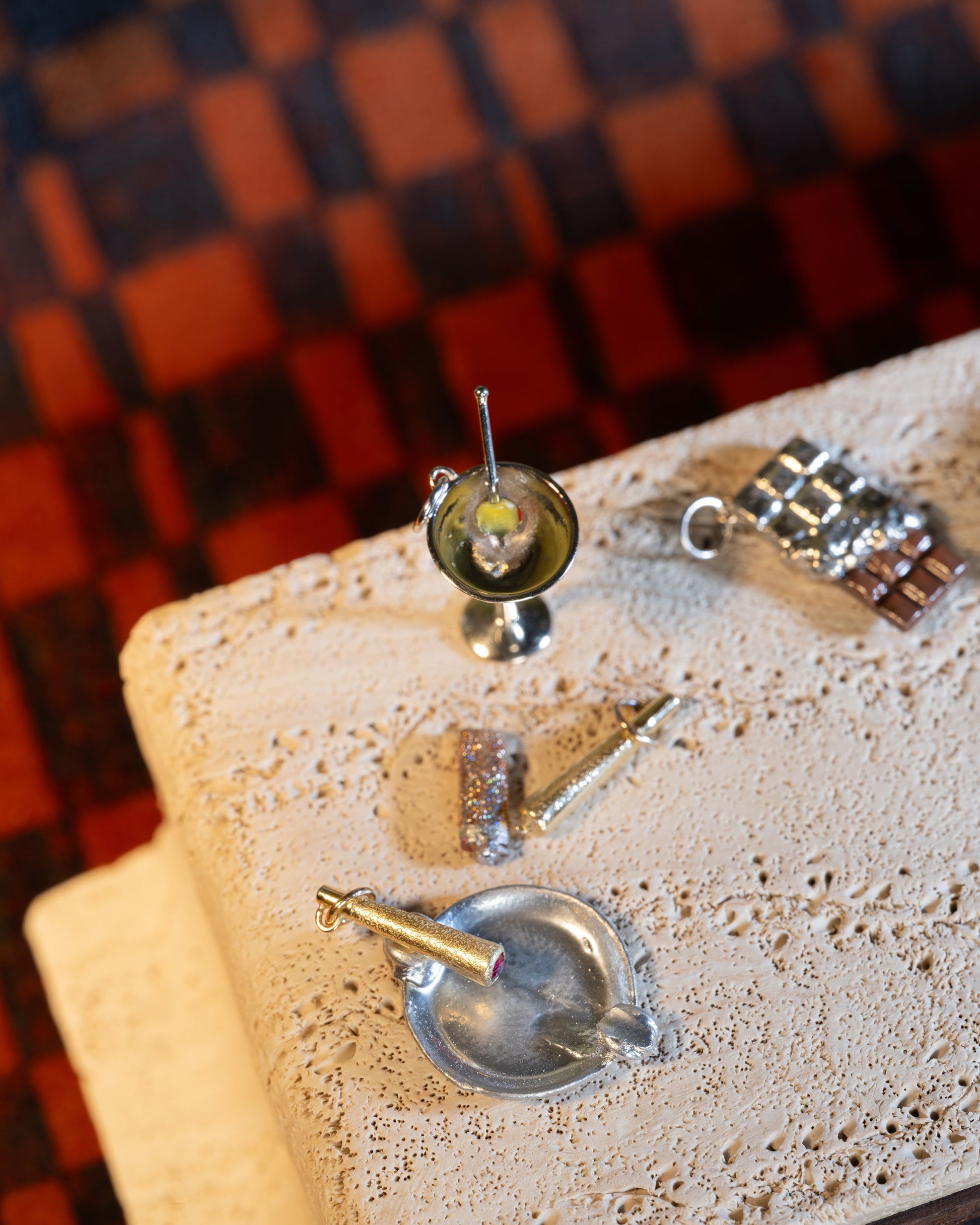 Styled image featuring the Joint Charm, Lit Joint Charm, Dirty Martini Charm and Chocolate Bar Charm.
