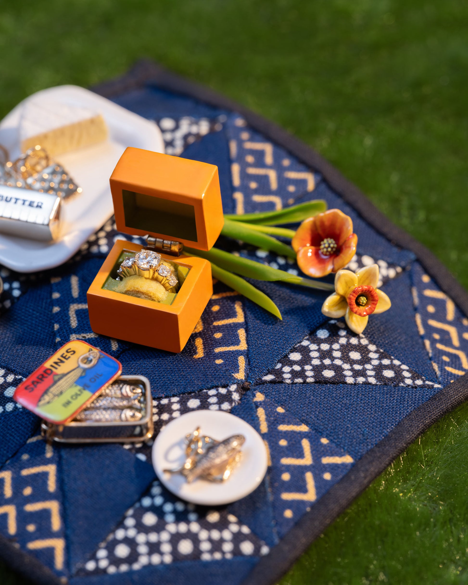 Styled image of the Luna Ring Charm, with the Salted Butter Charm, Sardine Can Charm, California Poppy Charm, Daffodil Charm, Sardine Fish Charm and Saltine Charms.