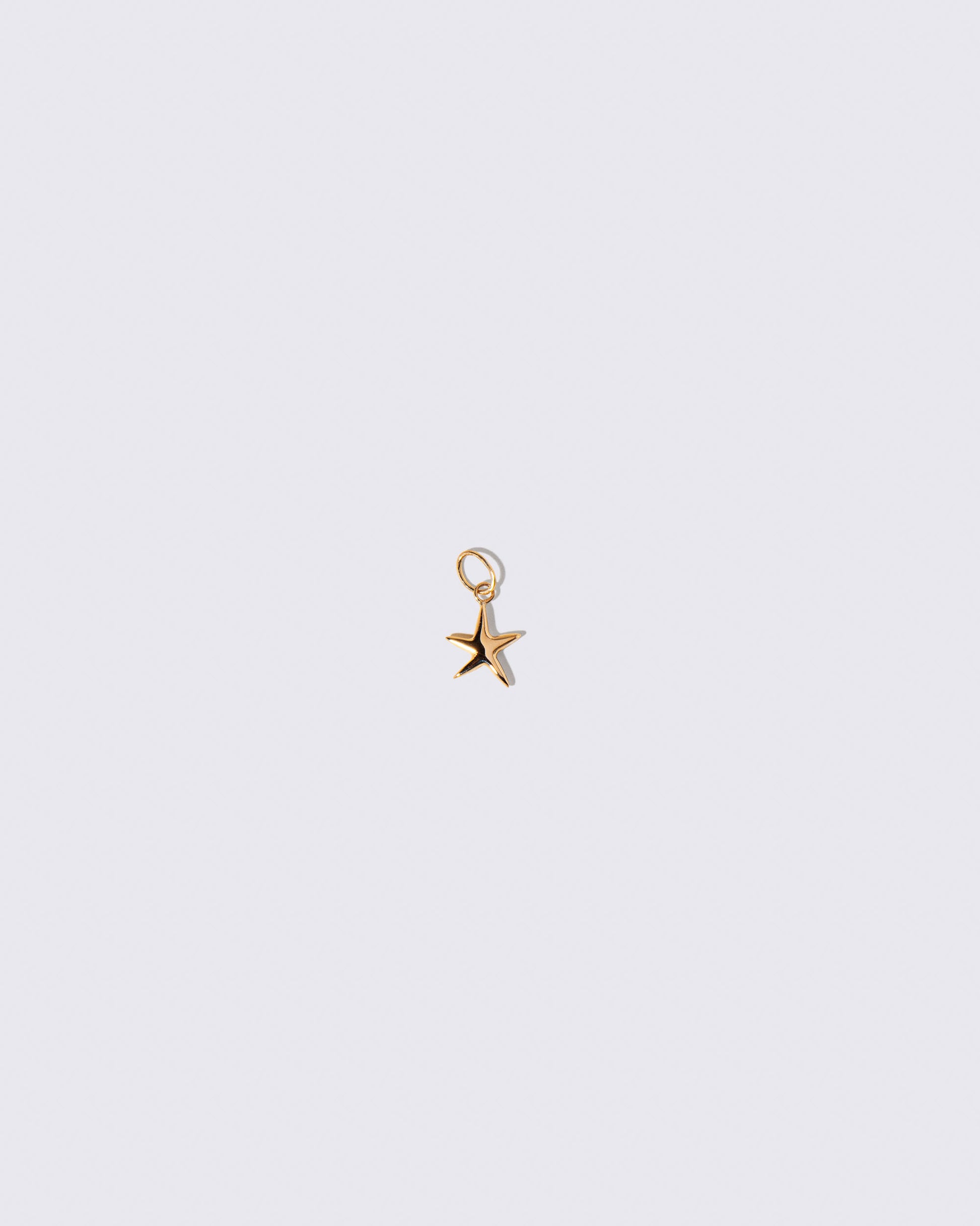 Gold Verve Five Point Star Charm on light color background.