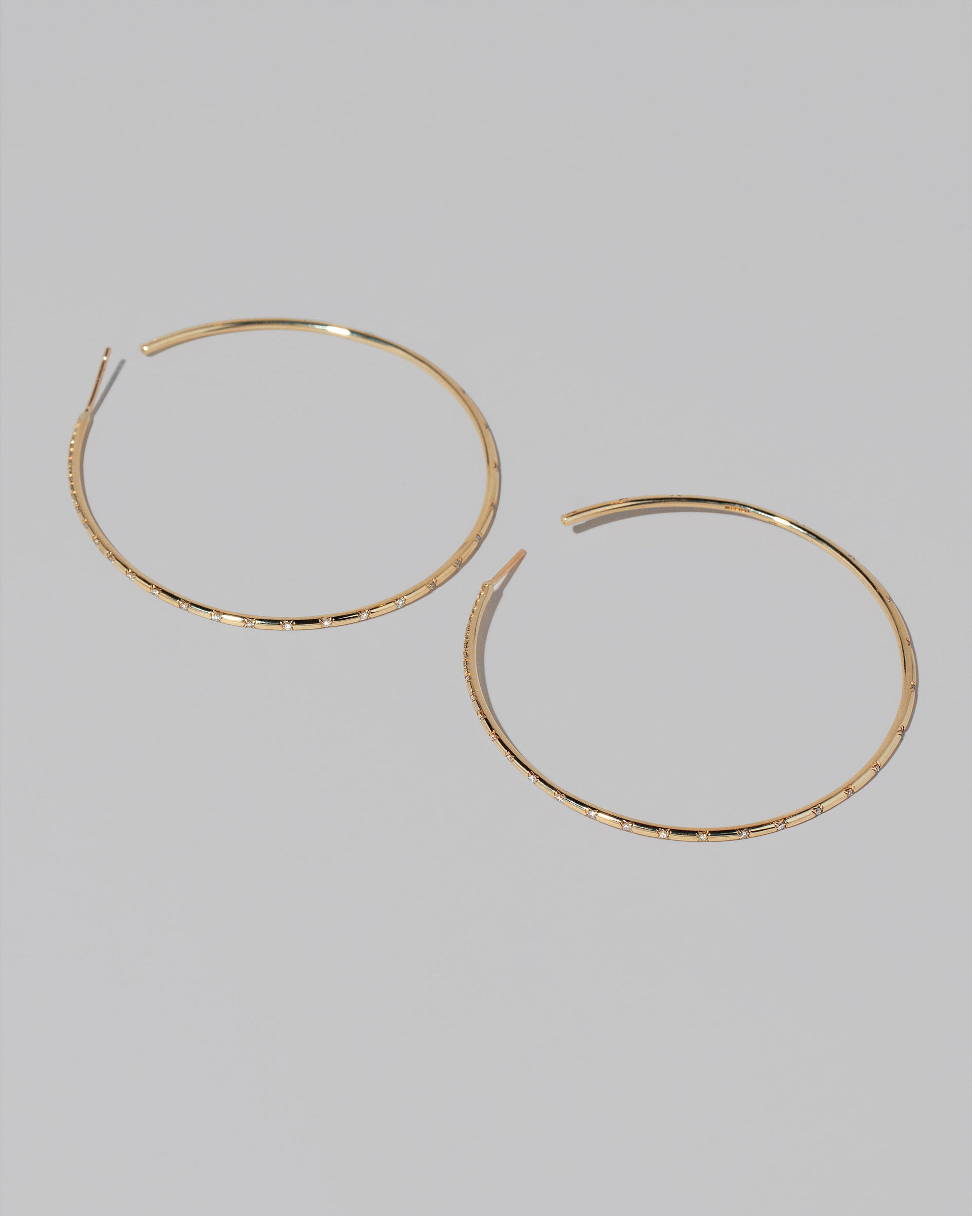 Large Pave Diamond Hoop Earrings on light color background.