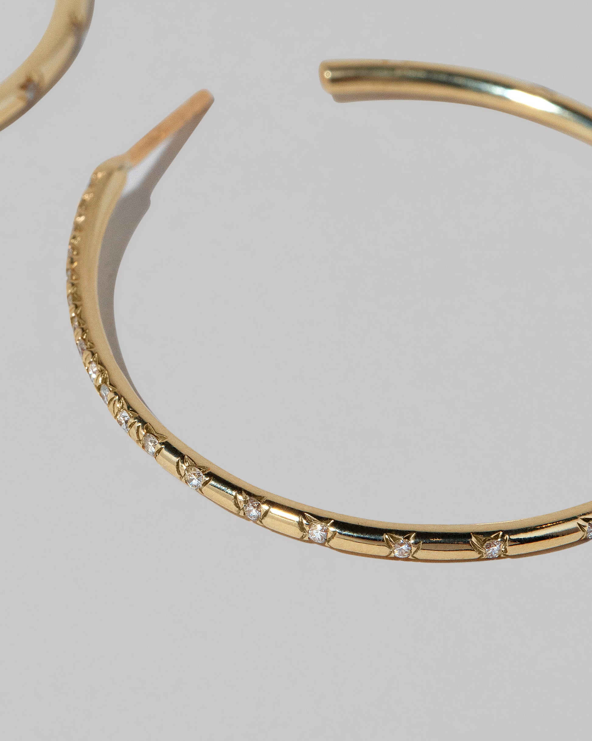 Closeup details of the Large Pave Diamond Hoop Earrings on light color background.