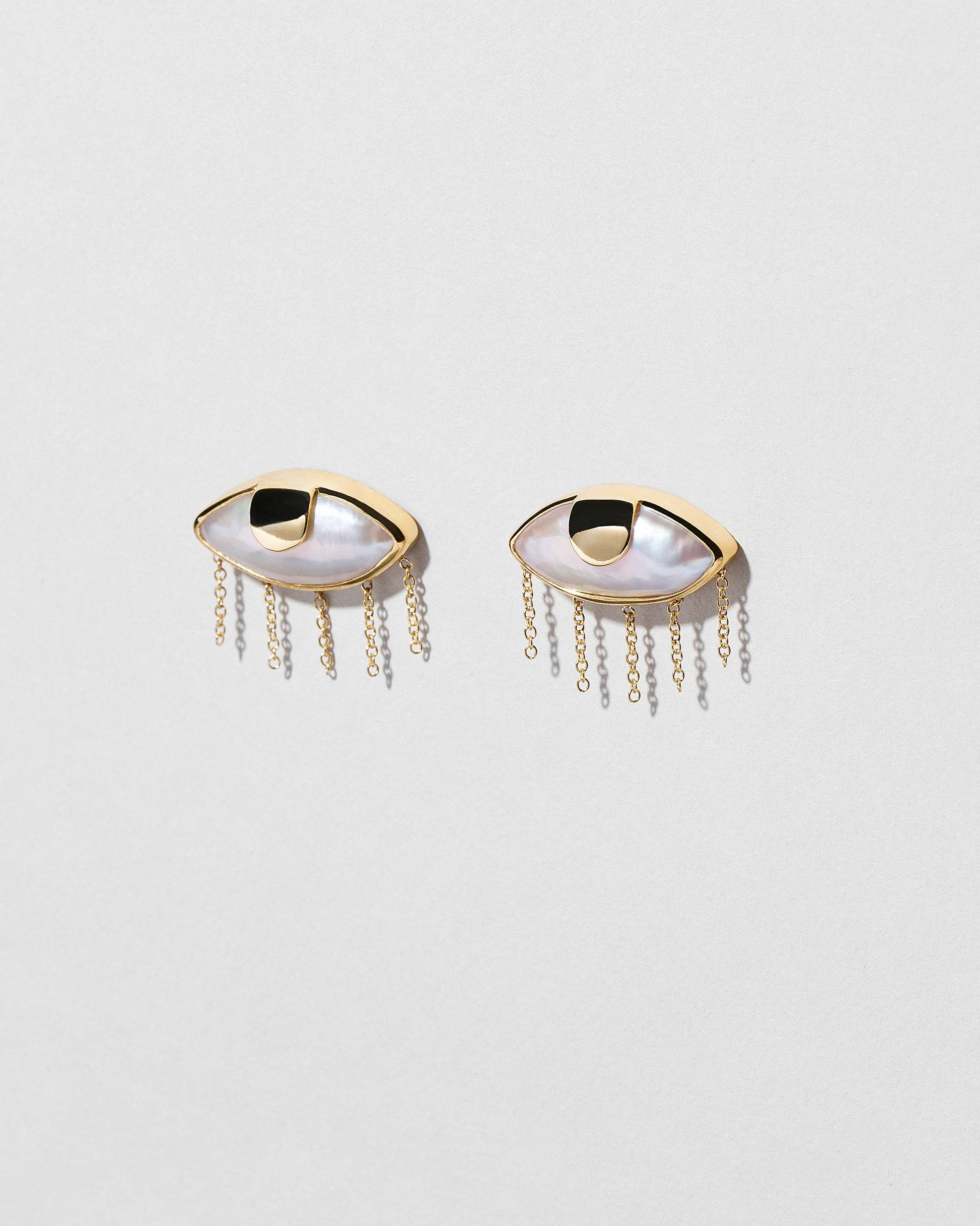 View from the side of the Pearl Eye Earrings on light color background.