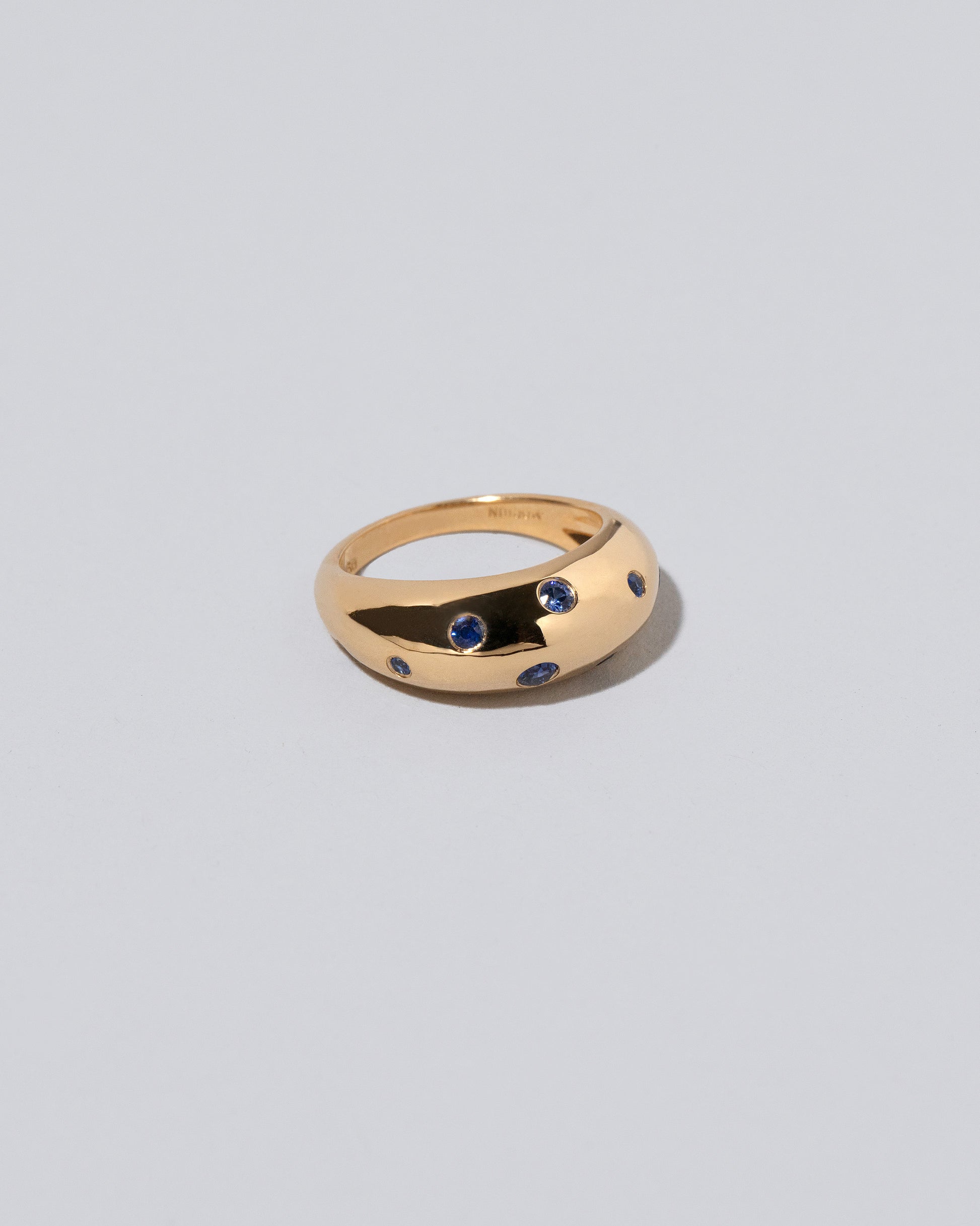 Closeup details of the Gold Blue Sapphire Brilliant Cuts Light Cutter Band on light color background.