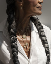Styled image on model featuring the Gold Oval Openable Link, Gold Butter Chain Necklace, Accumulation Necklace, Yellow Sapphire Gusher Charm Huggie Hoop Earrings, July Birthstone Pearl Pendant With Ruby, Peach Charm, Small Round Pendant Without Chain Memento Pendant, Grand Duality Medallion Pendant, Harmony Pendant and Diamond Poise Charms.