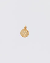 Finished Small Round Pendant Memento Pendant with engraved with a heart shape on light color background.