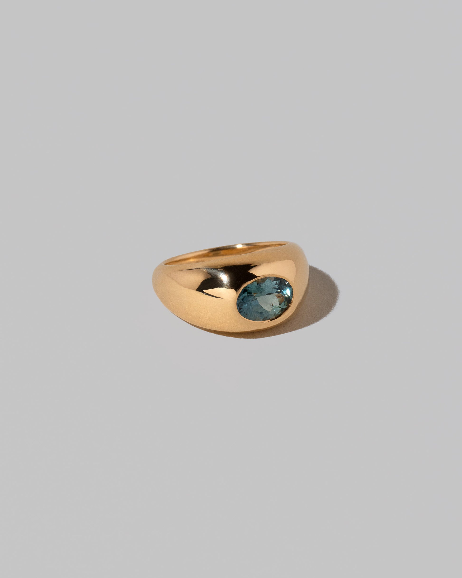View from the side of the Teal Sapphire Jupiter Ring on light color background.