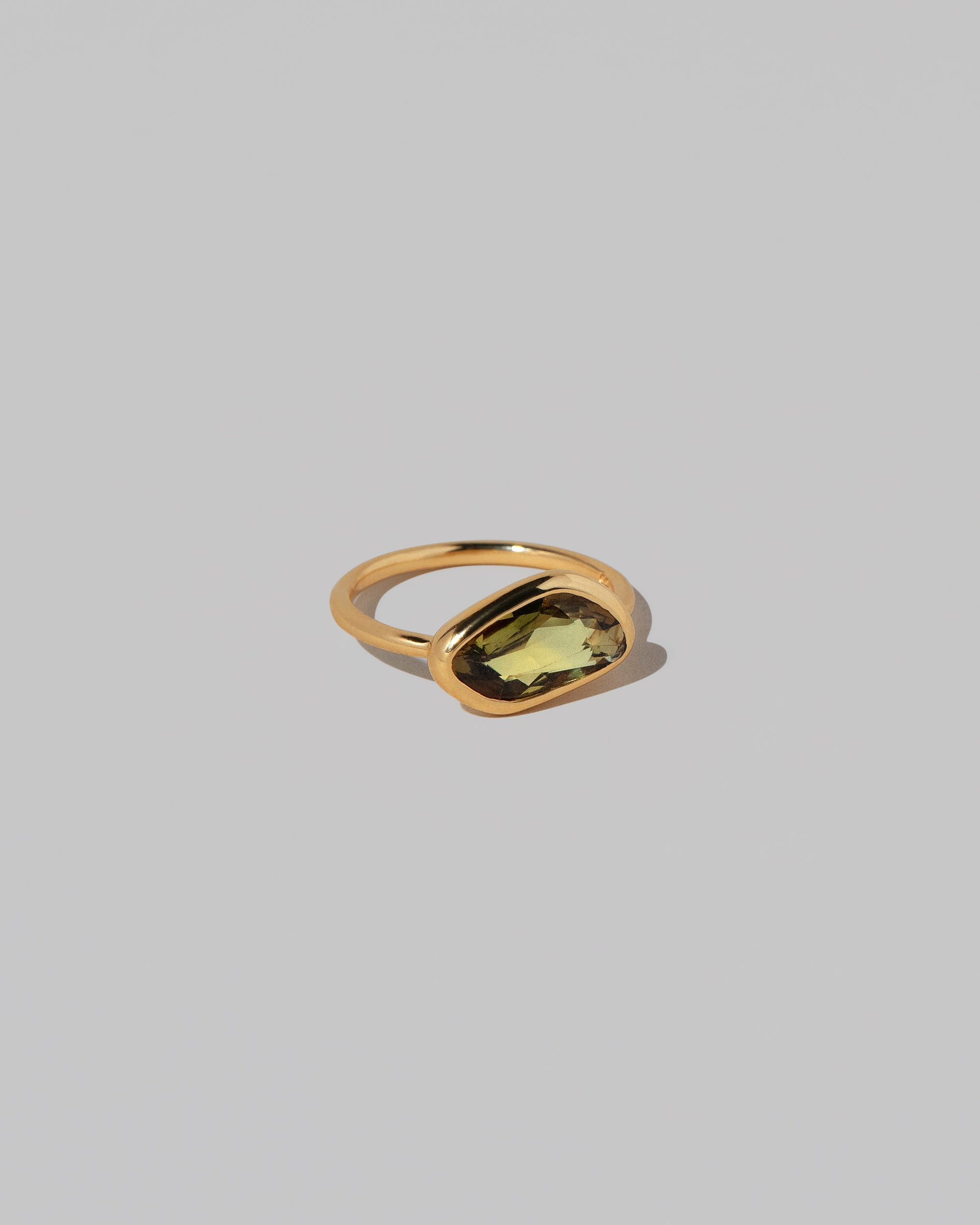 View from the side of the Gusher Green/Yellow Sapphire Ring 034 on light color background.