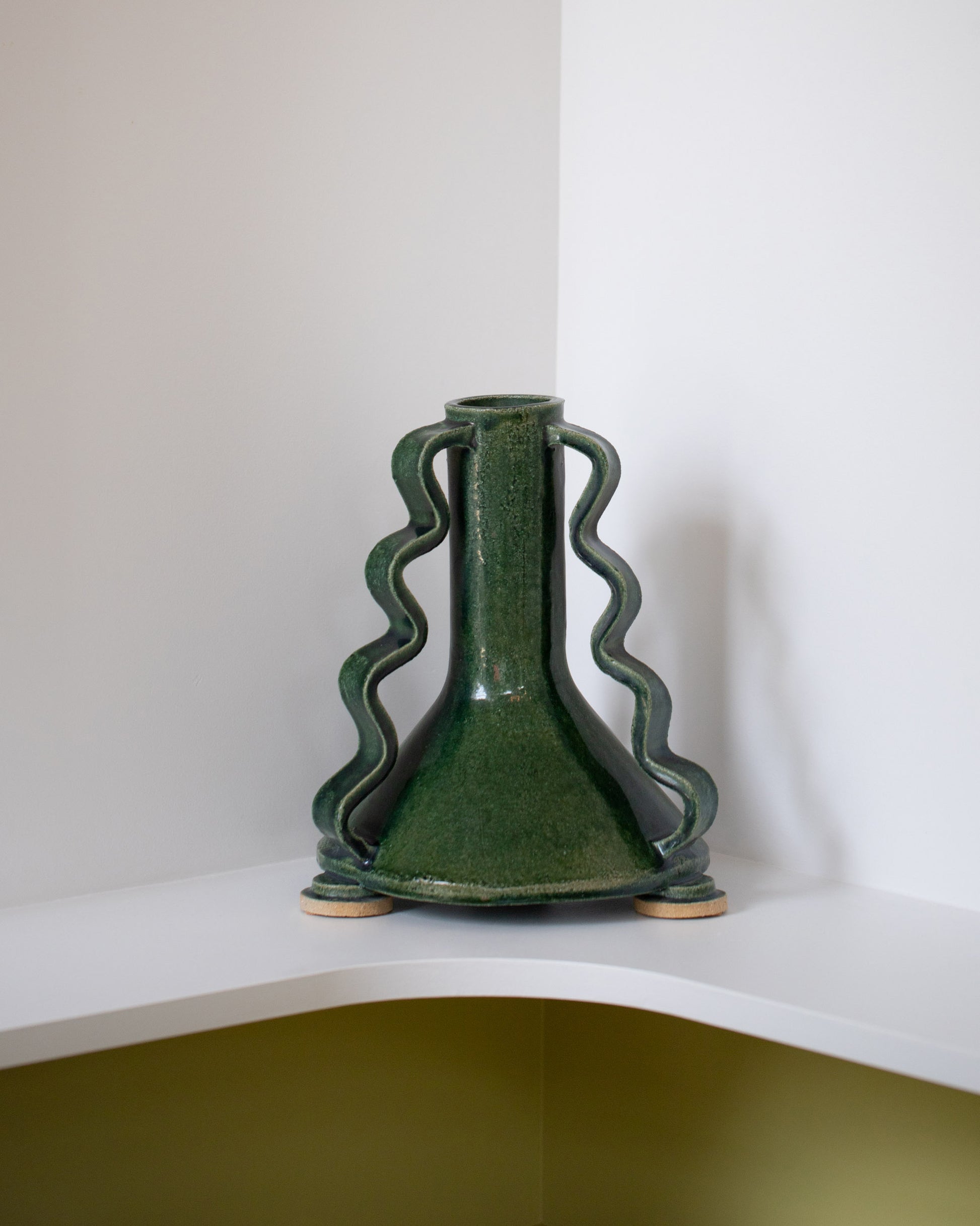 Morgan Peck Glassy Green Swoop Vase on light color background.