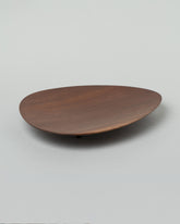 Namu Home Goods Black Walnut Asymmetrical Footed Plate on light color background.