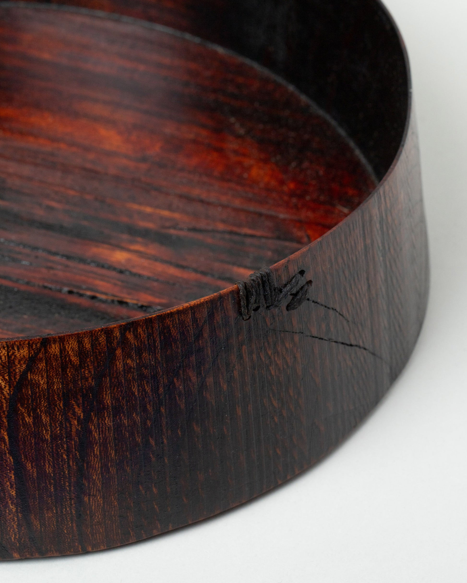 Closeup details of the Namu Home Goods Zelkova Wood Medium Red Lacquered Bowl on light color background.