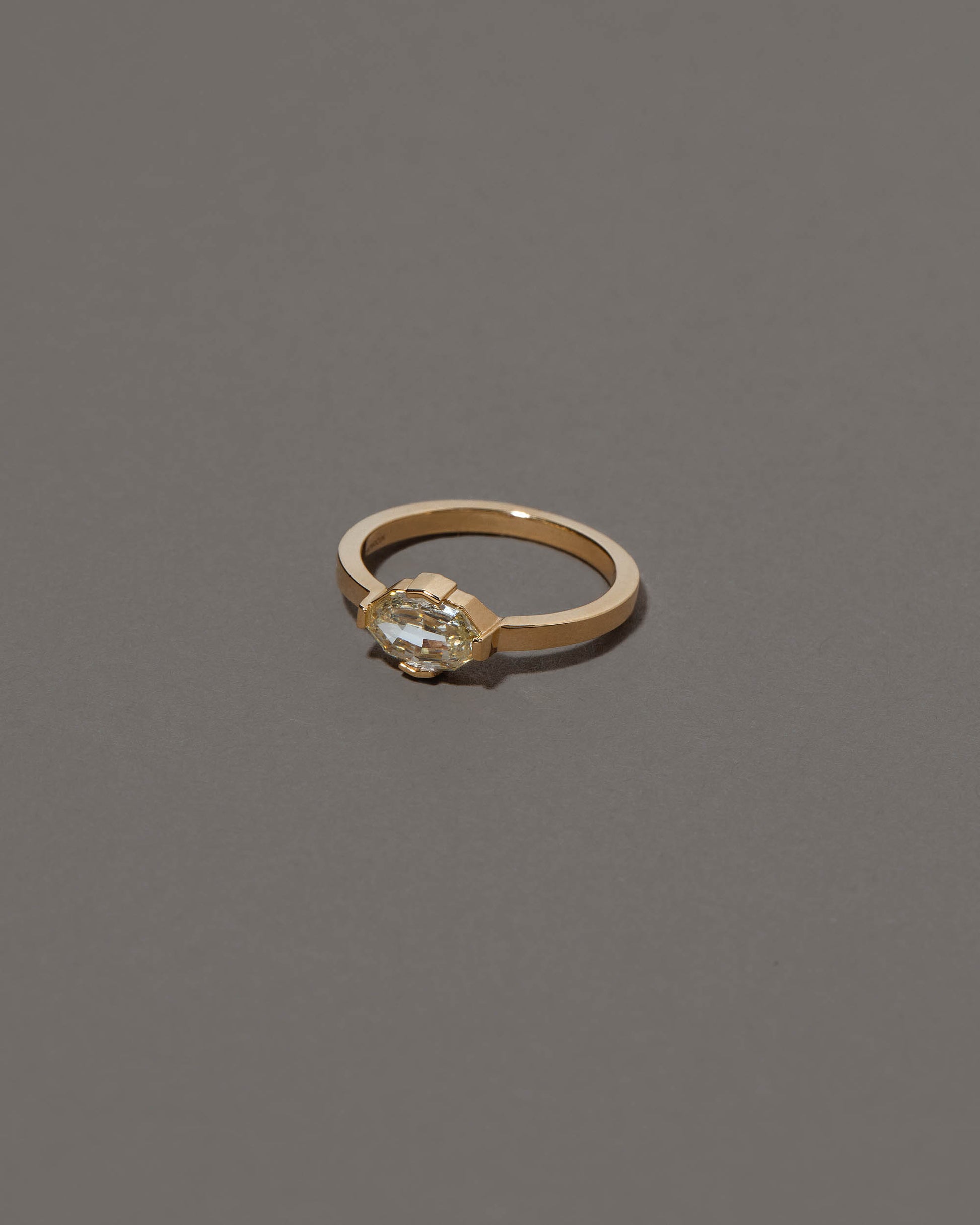 View from the side of the Beholden Ring on grey color background.