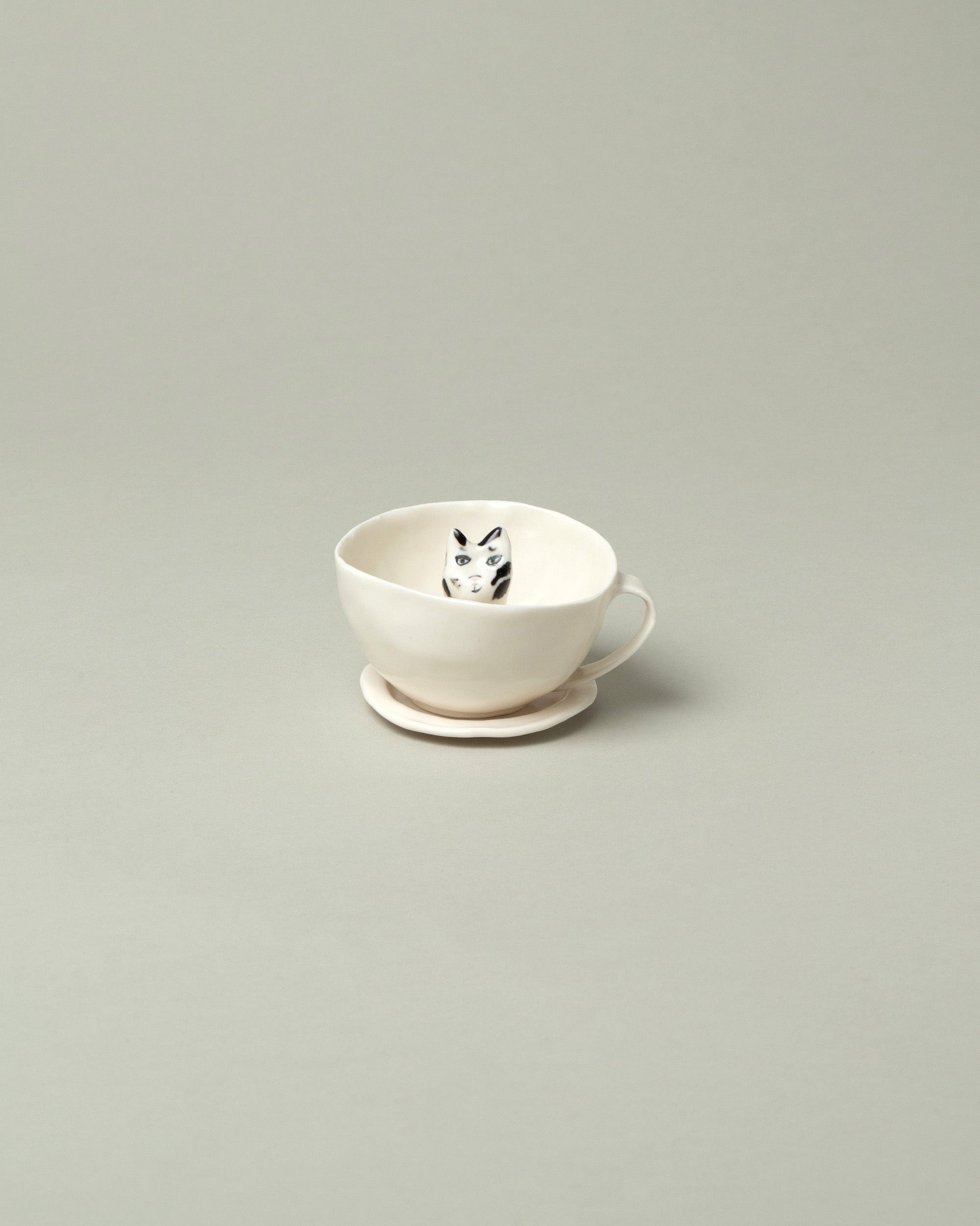 Eleonor Boström Black Spots Cat Tea Cup with Saucer on light color background.