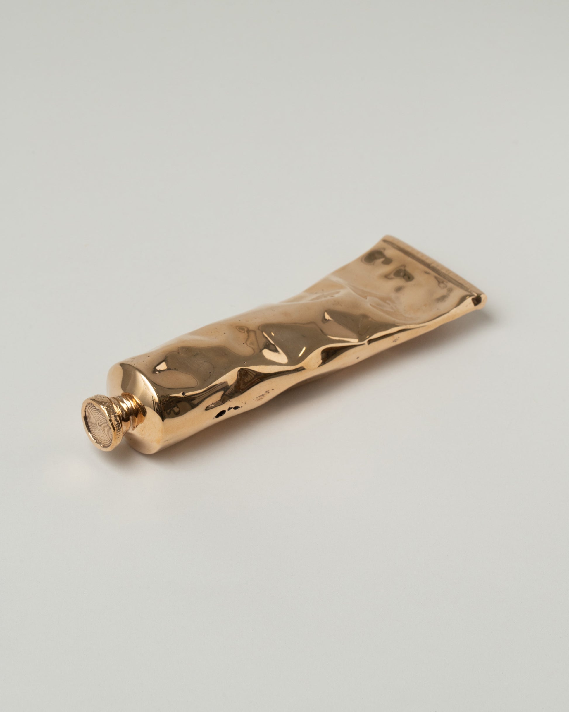 Pearce Objects Cast Bronze Paint Tube on light color background.