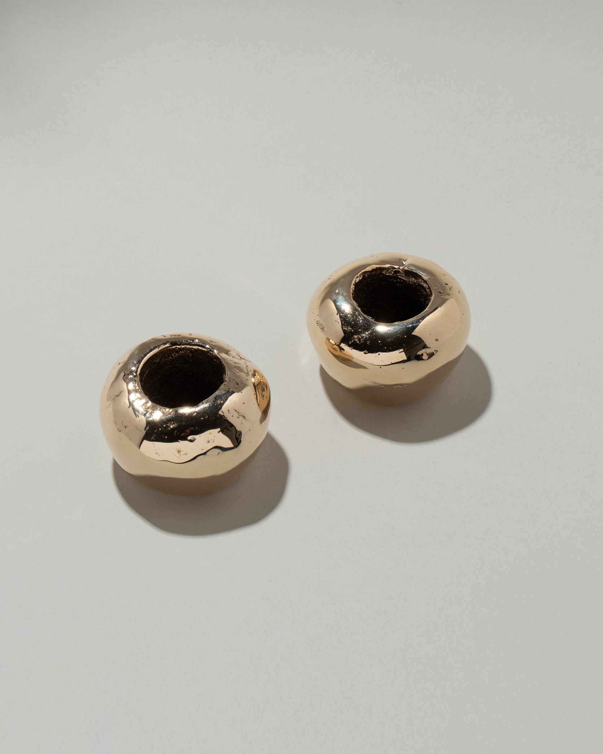 Pearce Objects Cast Bronze Globular Candle Holder Set on light color background.