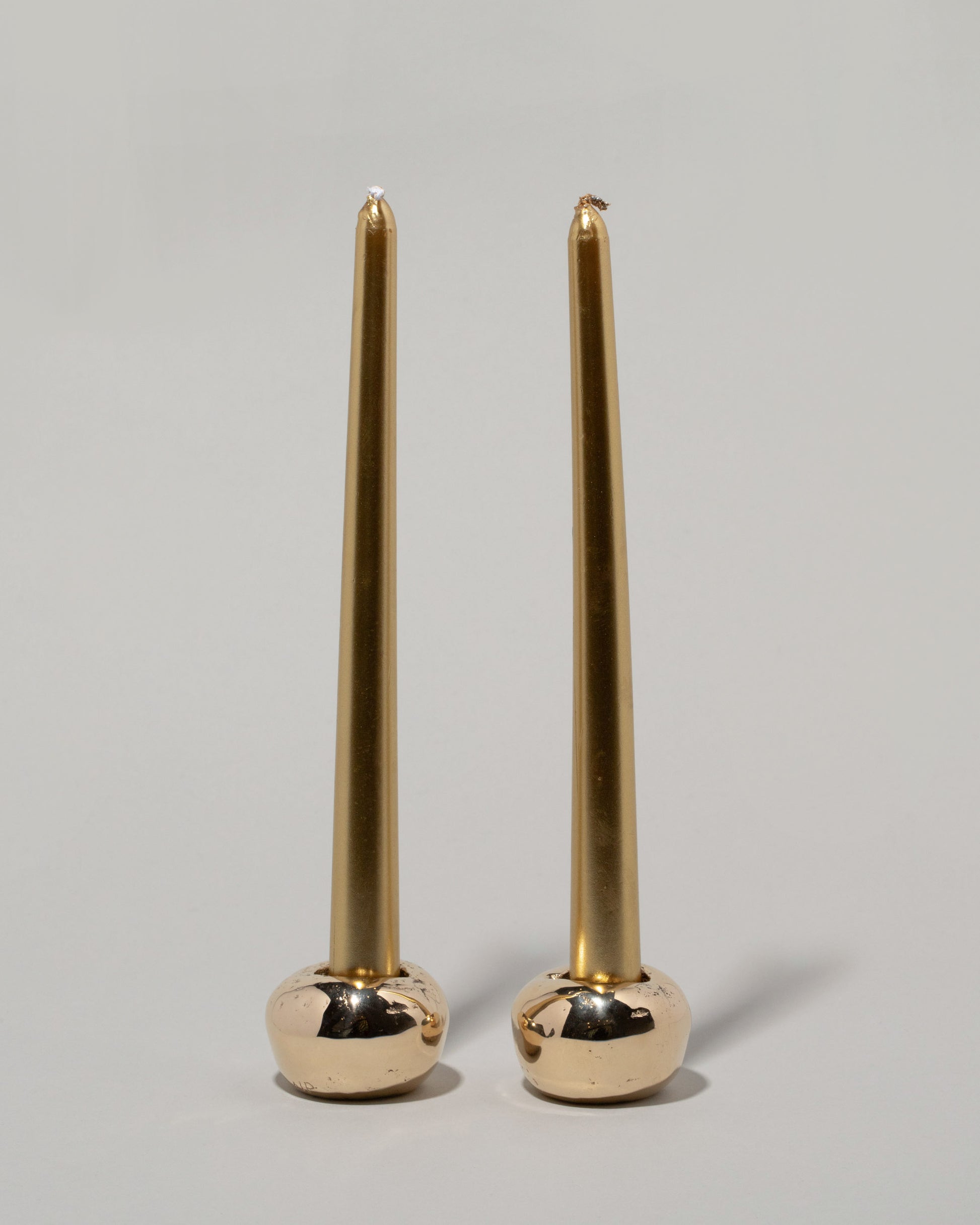 Pearce Objects Cast Bronze Globular Candle Holder Set with candles on light color background.