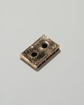 Closeup details of the Pearce Objects Cast Bronze Mini Cassette Tape on light color background.