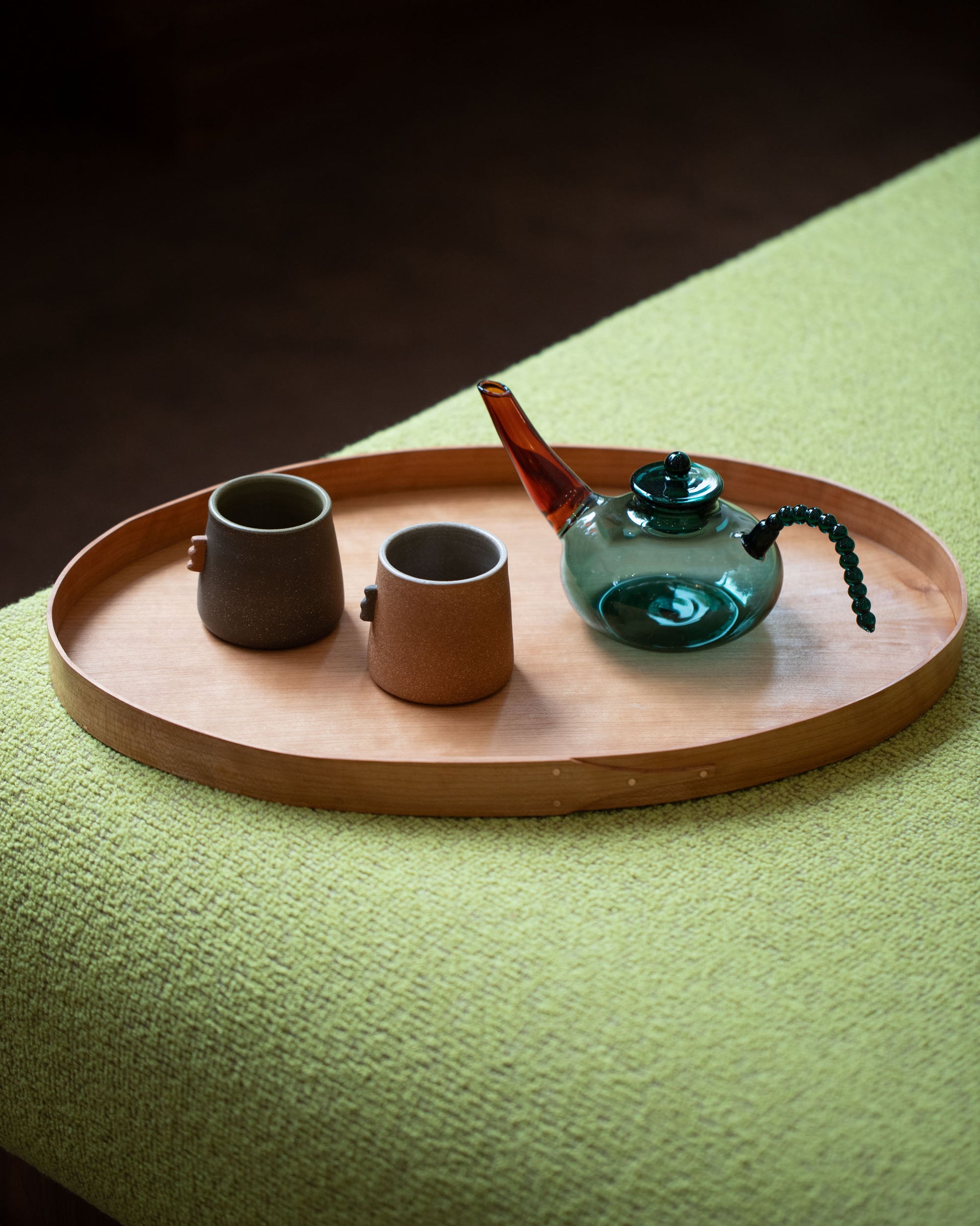 Styled image featuring the Rikke Falkow Large Cherry Wood Serving Tray, with the Ornamental by Lameice Teal & Amber Dreamlike Teapot and Emris Brick Clay and Dark Stoneware Nub Cups.
