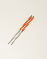 Sabre Paris Orange Chopsticks on light color background.