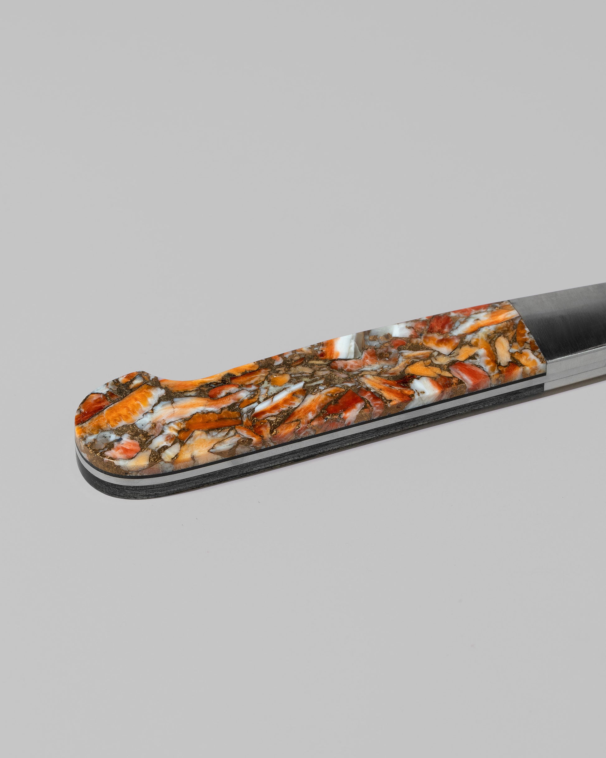 Closeup details of the Santa Fe Stoneworks Spiney Oyster Bread Knife on light color background.