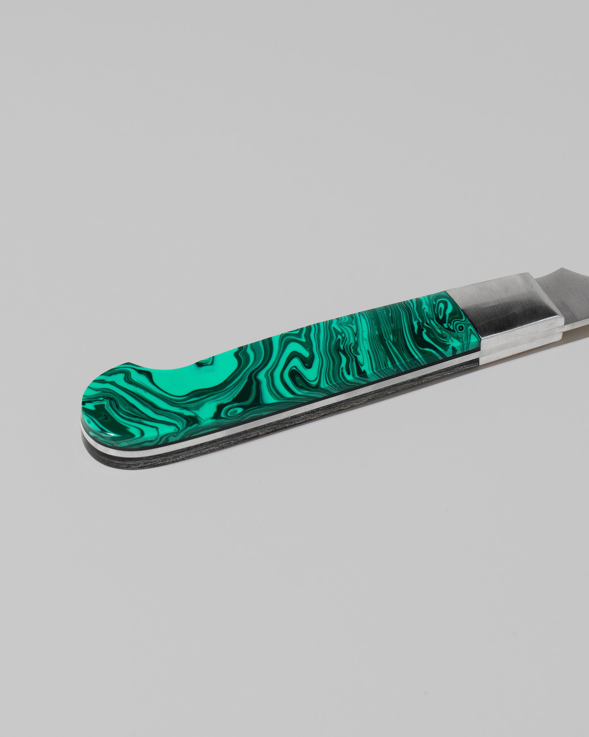 Closeup details of the Santa Fe Stoneworks Tru Stone Malachite Bread Knife on light color background.