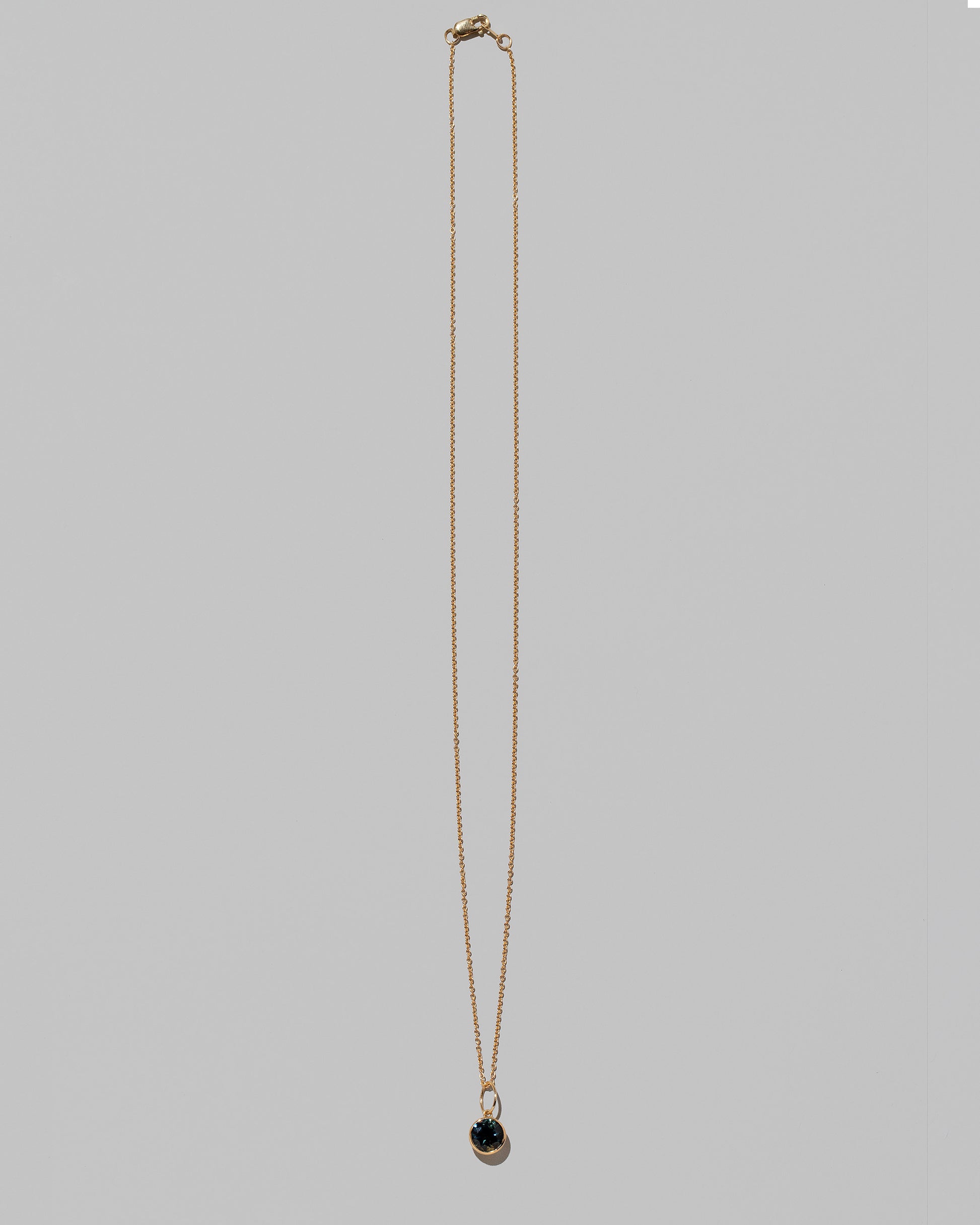 Bicolor Sapphire Pendant paired with chain on light color background.