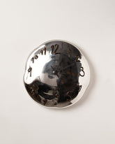 Silje Lindrup Black Hands One Brown Glass Wall Clock on light color background.