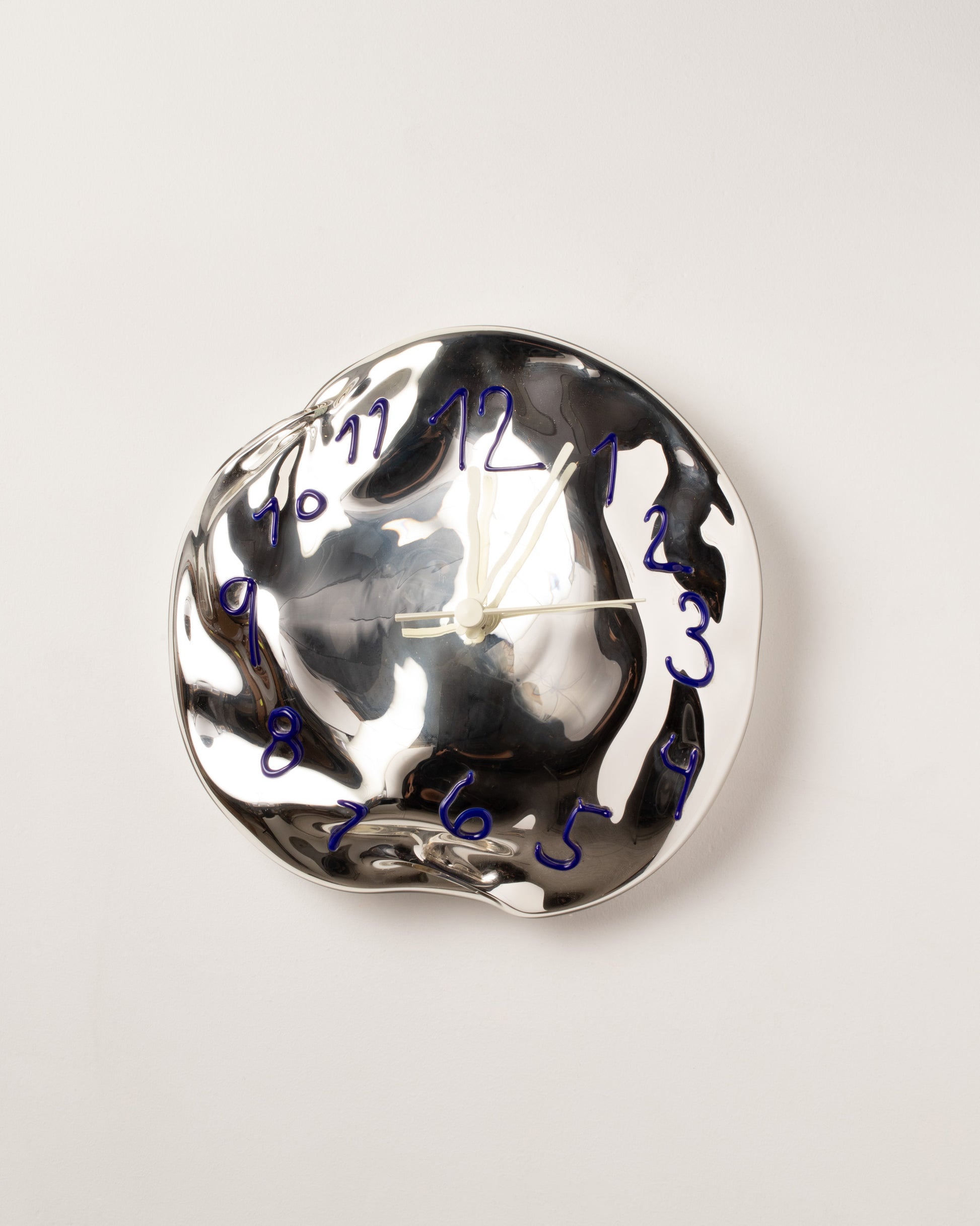 Silje Lindrup White Hands Blue Glass Wall Clock on light color background.