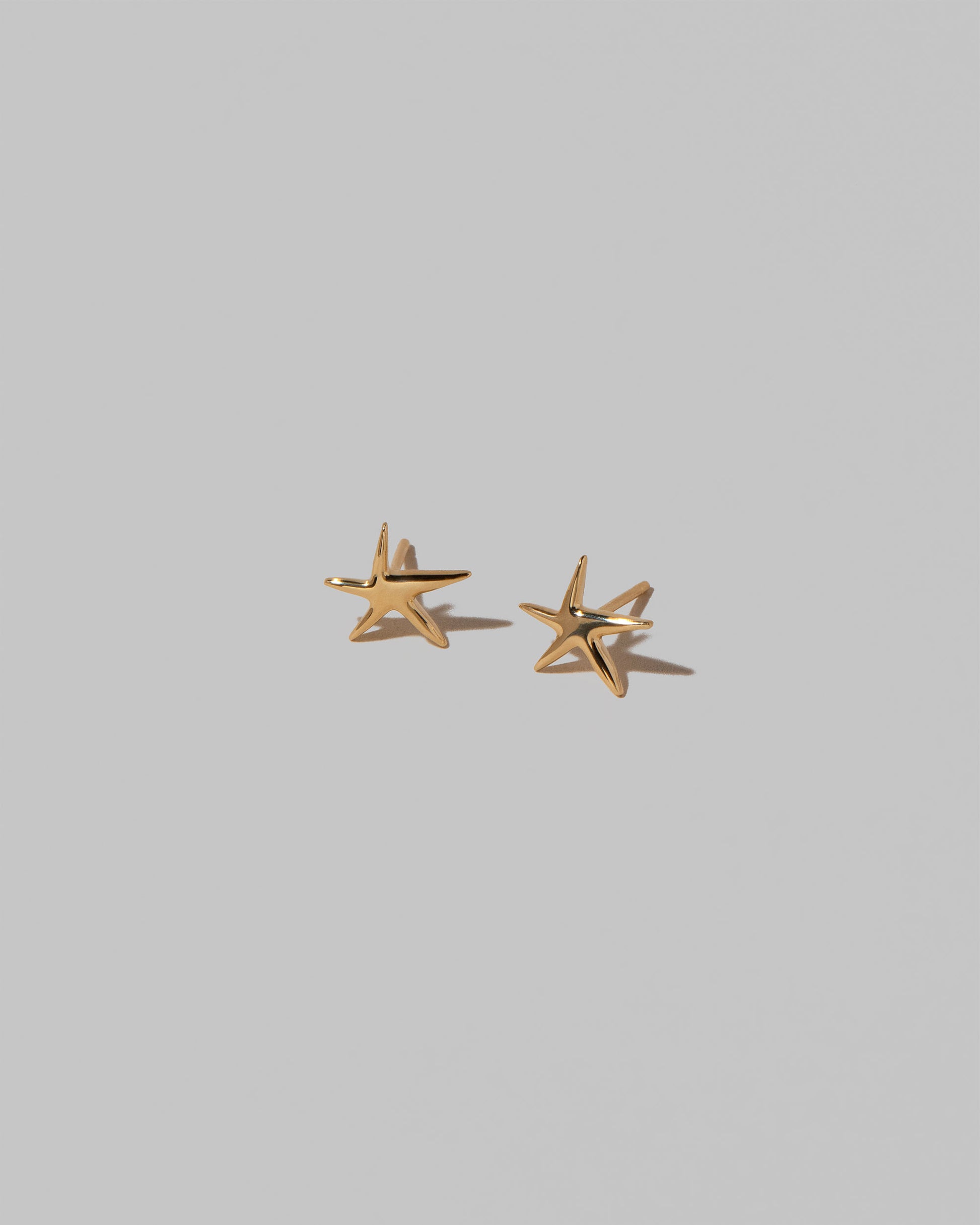 Shape Two Small Verve Five Point Star Stud Earrings on light color background.