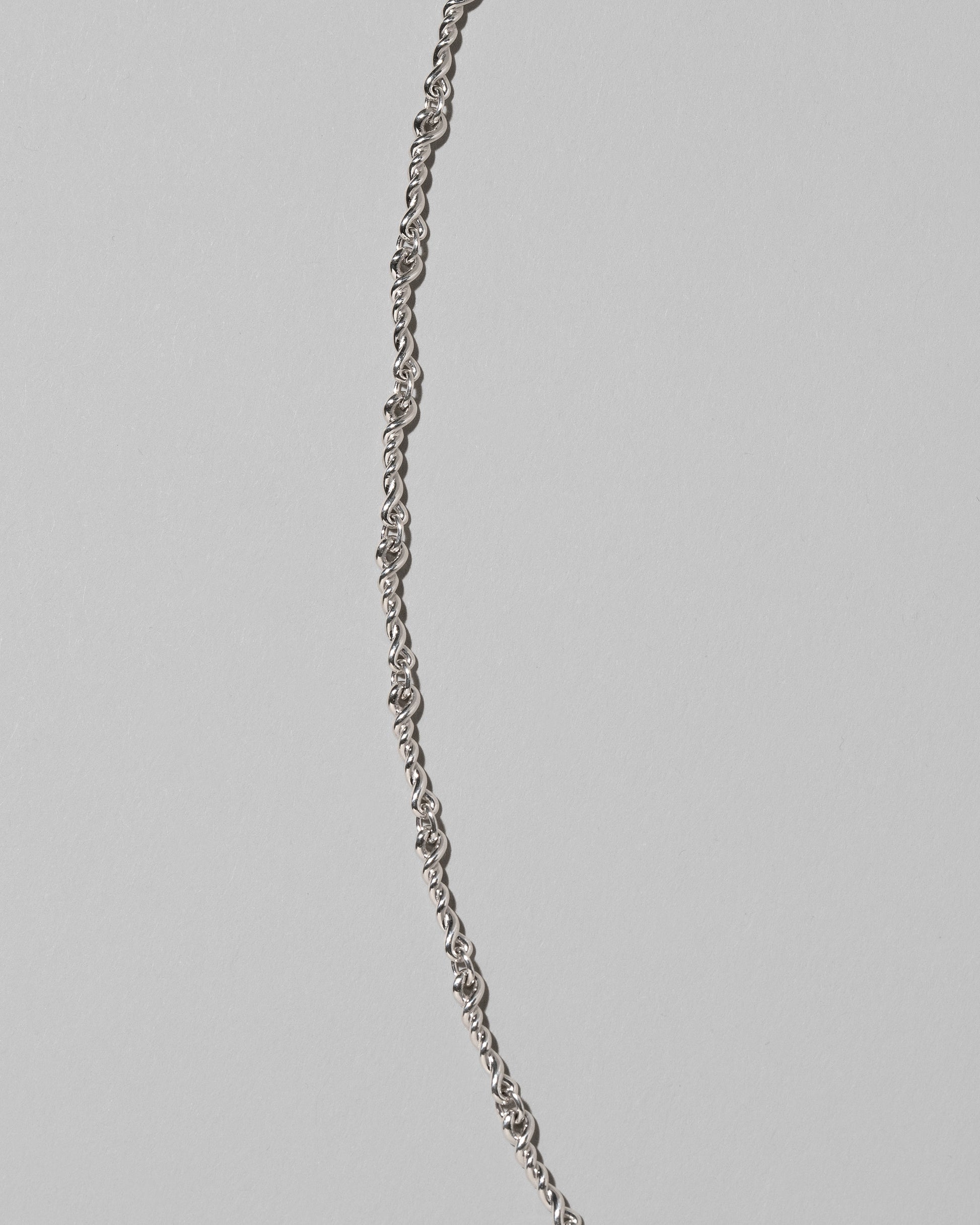 Closeup details of the CRZM Sterling Silver Double Helix Chain Necklace on light color background.