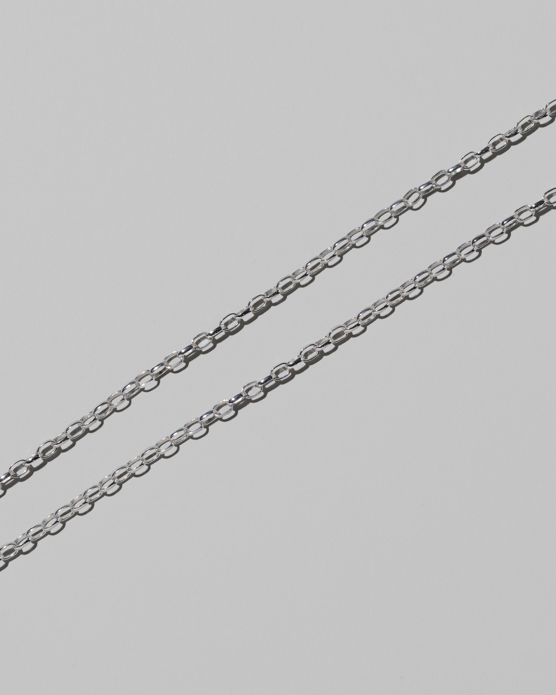 Closeup details of the CRZM 2mm Sterling Silver Short Loop Chain Necklace on light color background.