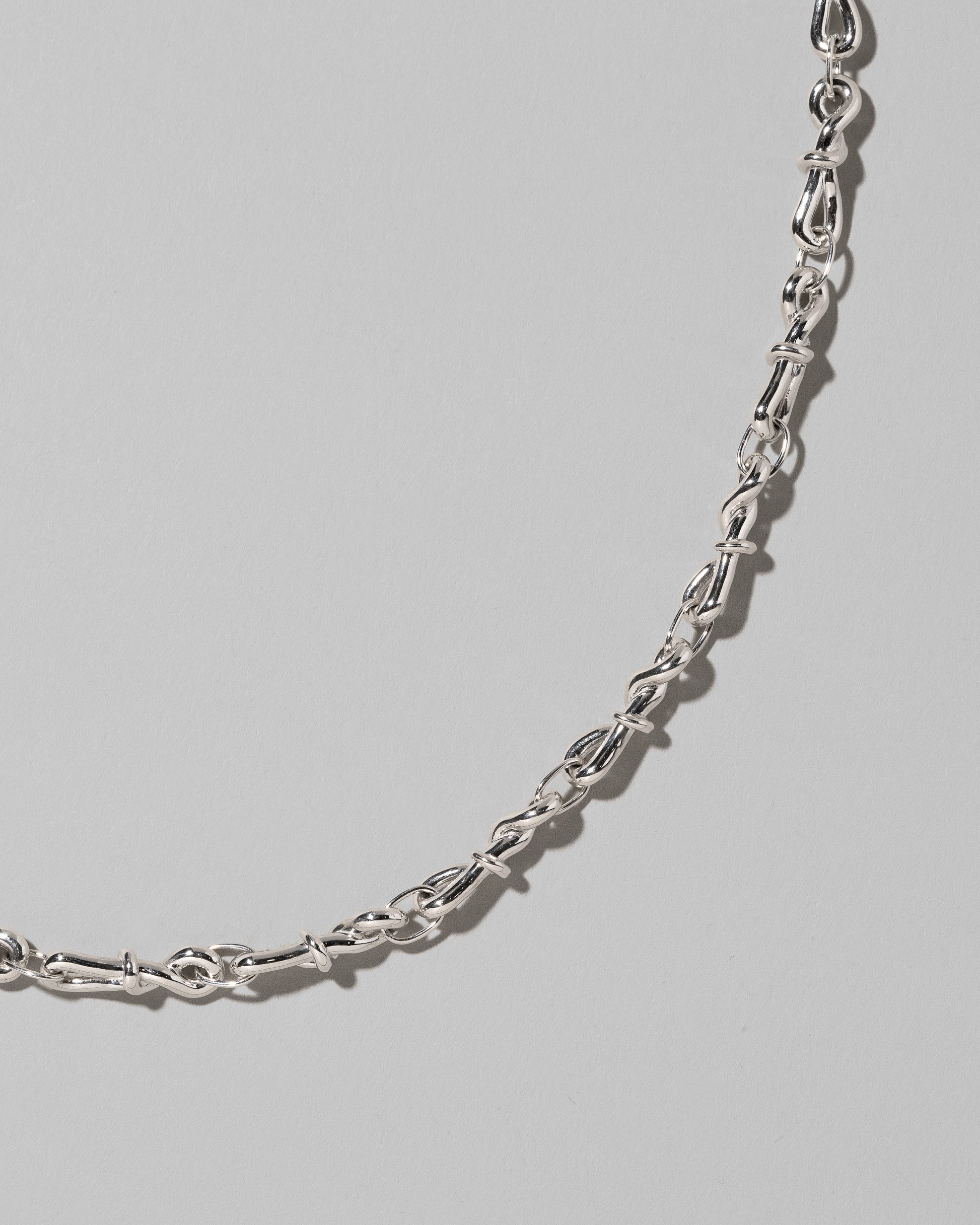 Closeup details of the CRZM Sterling Silver Torsional Chain Necklace on light color background.