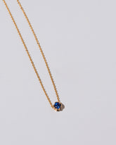 Closeup view of the Sapphire Sun & Moon Necklace on light color background.