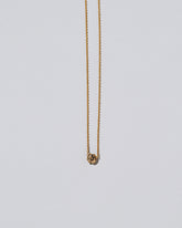 Closeup view of the Champagne Diamond Sun & Moon Necklace on light color background.