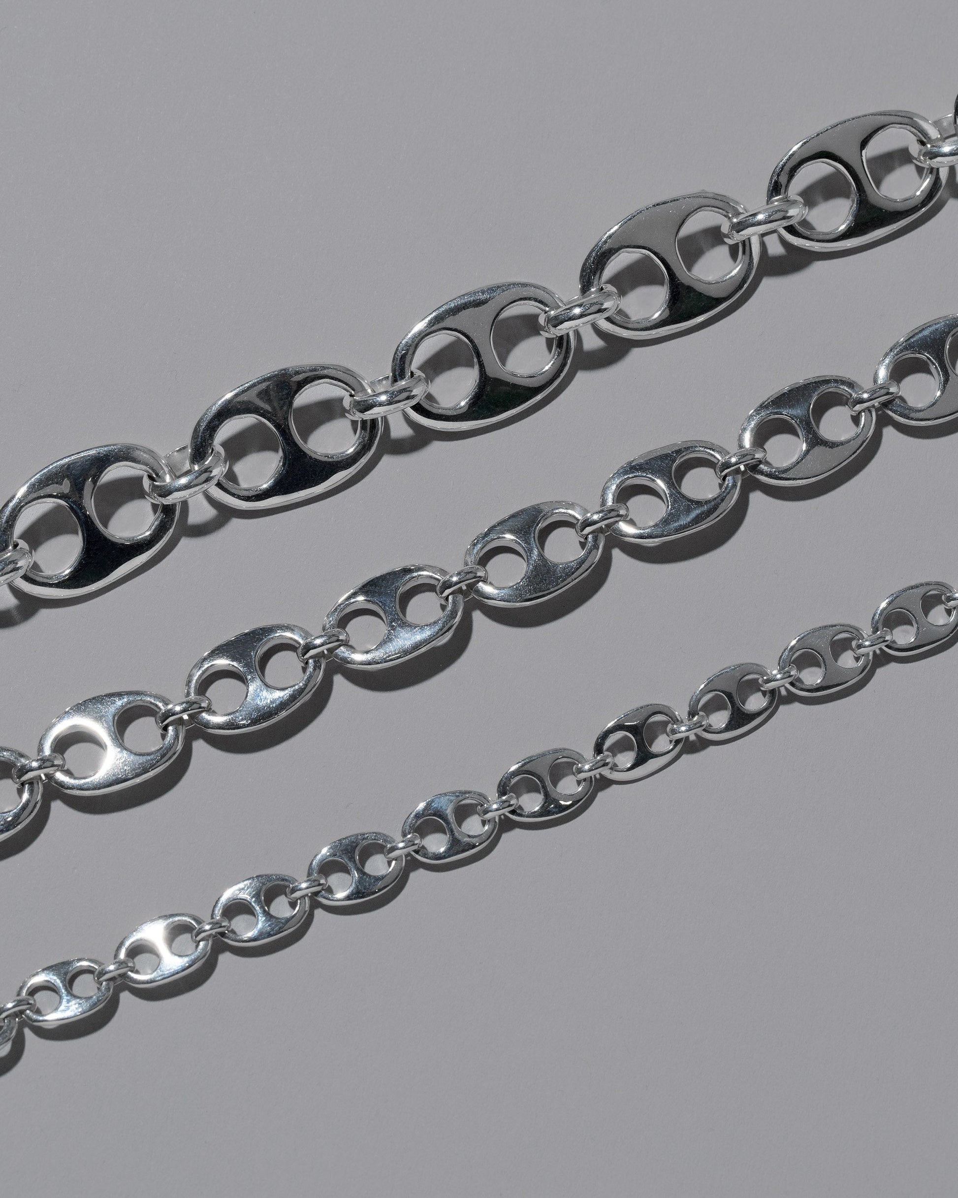 Closeup details of the CRZM Sterling Silver Yuba Mini Necklace, Sterling Silver Yuba Medium Necklace, and Sterling Silver Yuba Necklace on light color background.