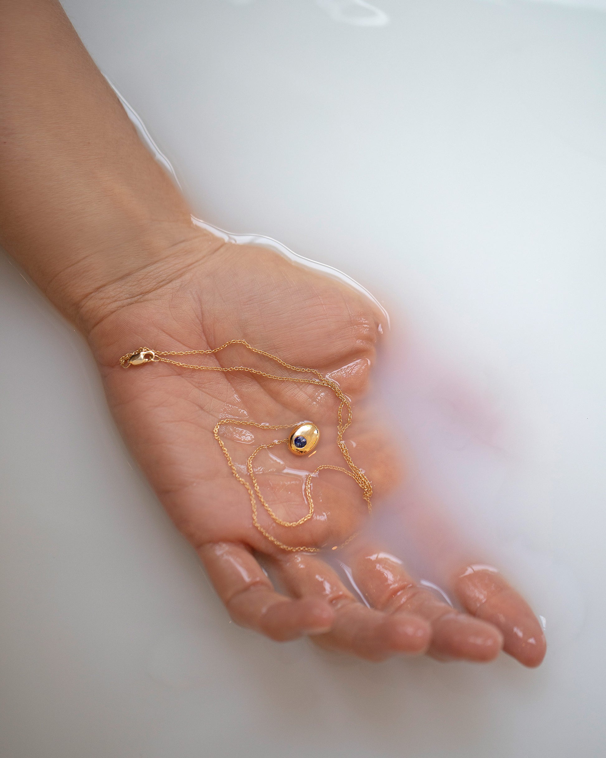 Styled image of the Gold Bicolor Blue Sapphire Level Necklace in hand.