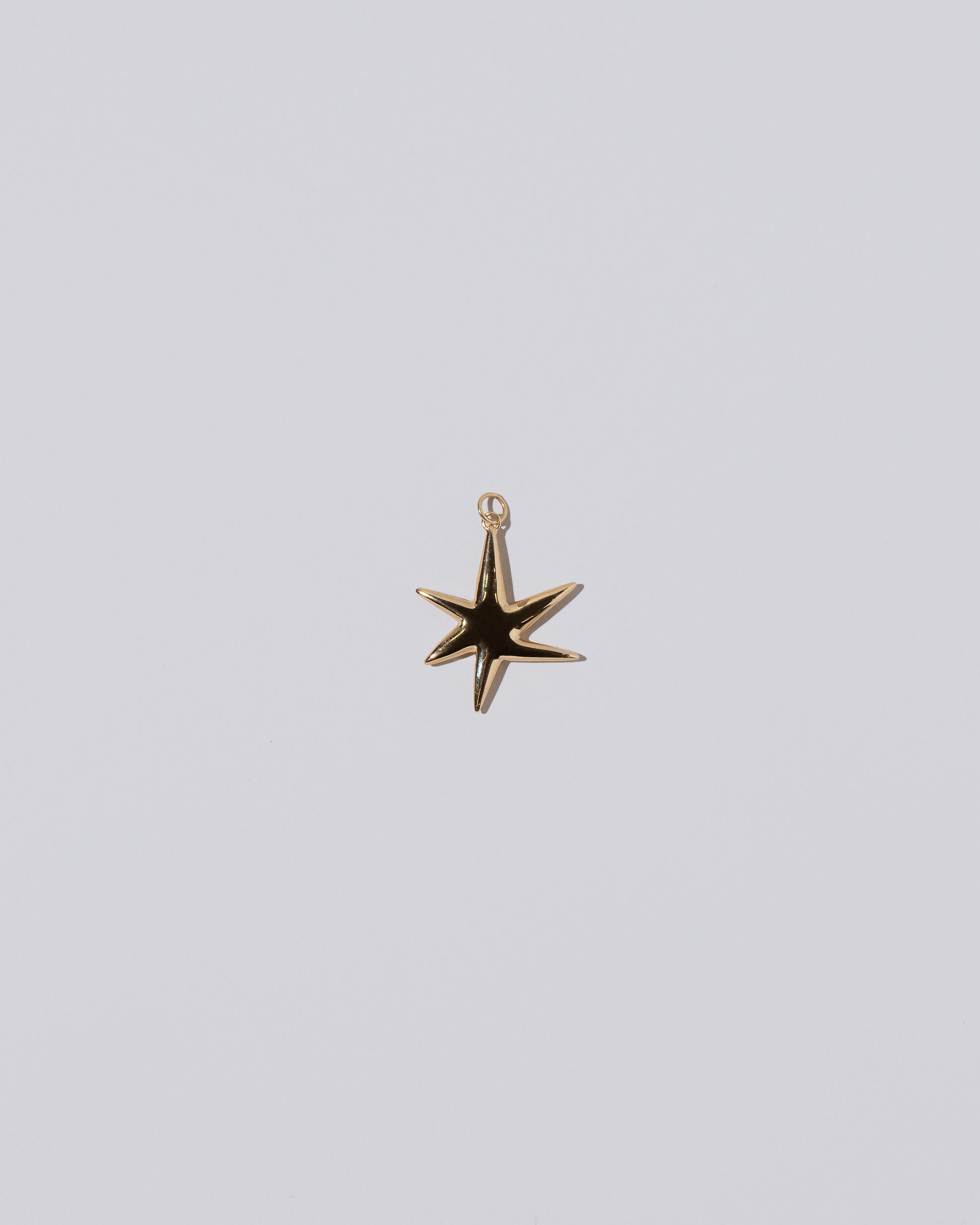 Verve Six Point Star Charm on light color background.