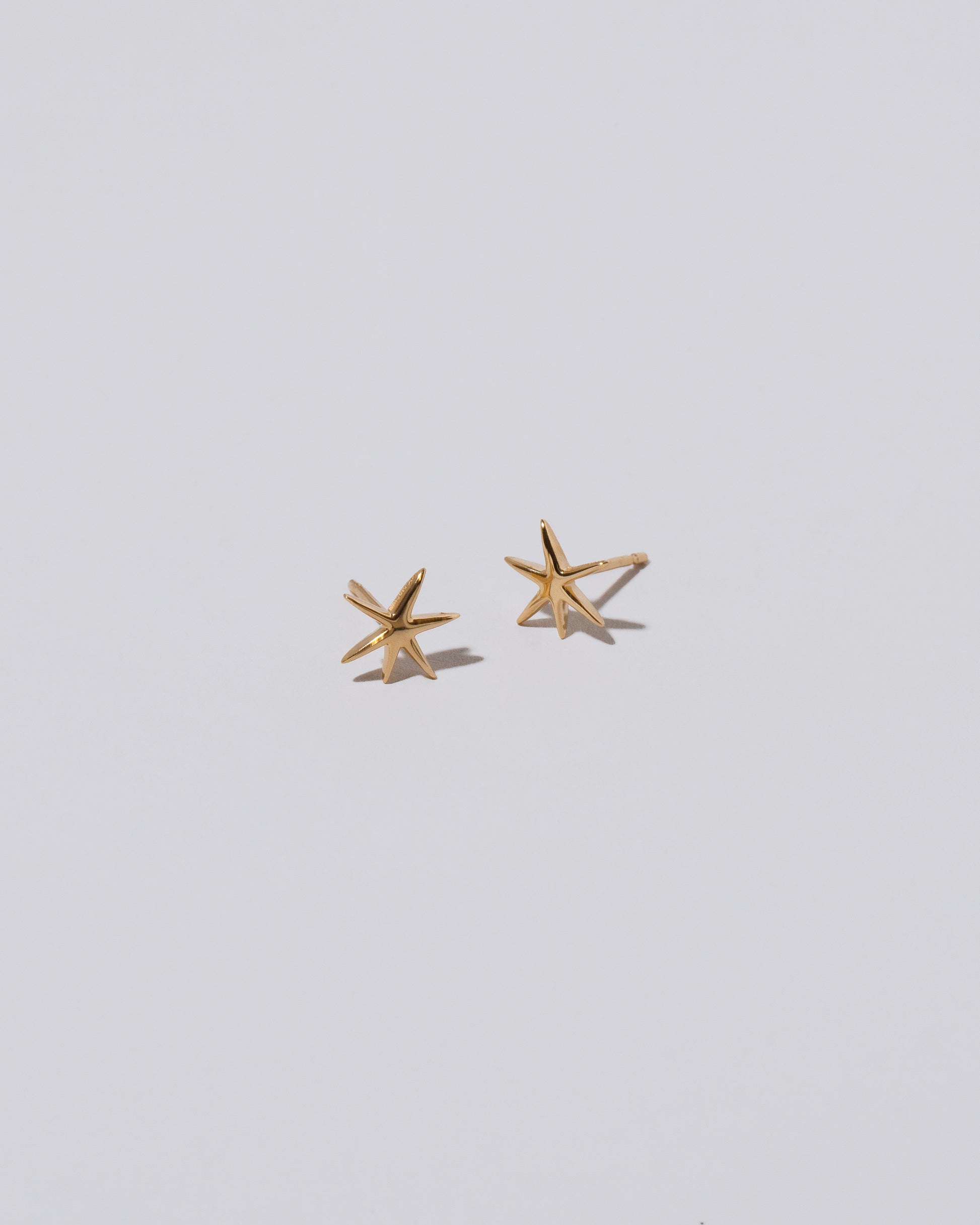 Shape Two Small Verve Six Point Star Stud Earrings on light color background.