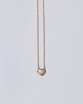 Closeup detail of the Lunar Heart Necklace on light color background.