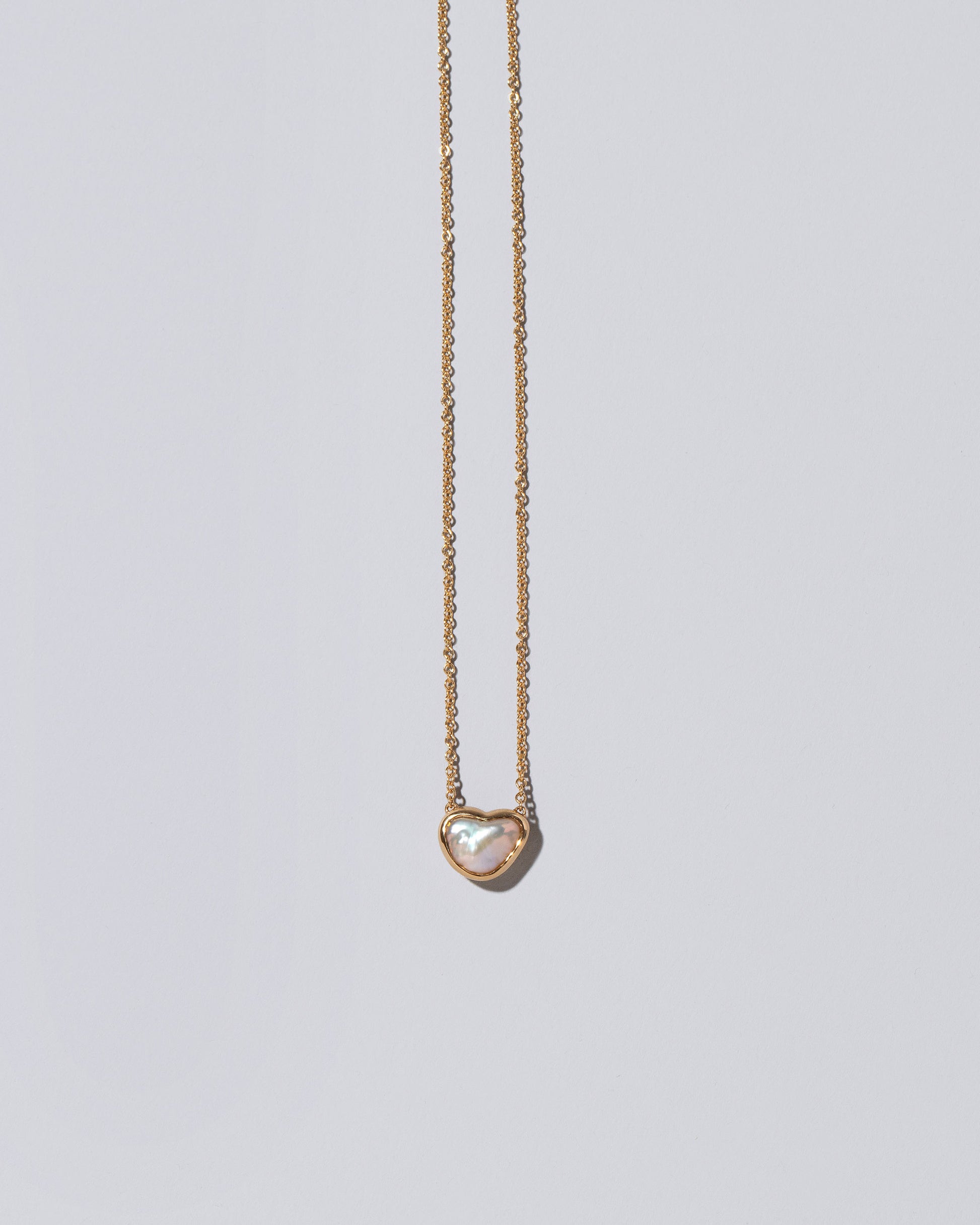 Closeup detail of the Lunar Heart Necklace on light color background.