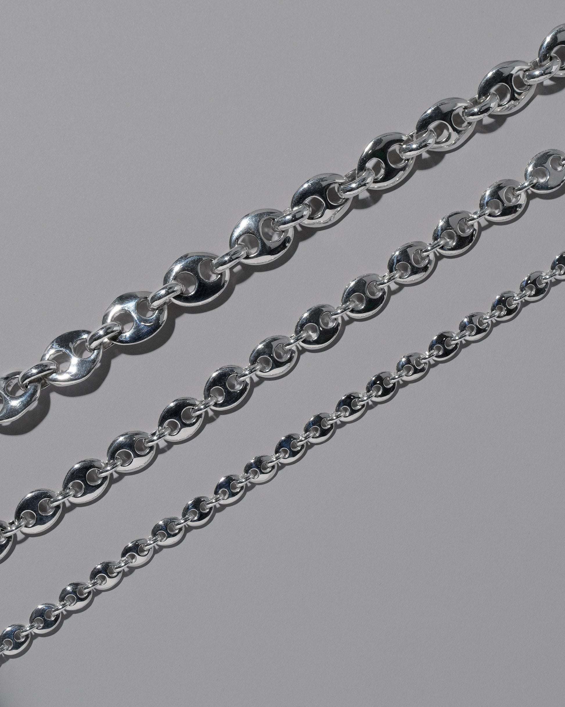 Closeup details of the CRZM Sterling Silver Bedrock Mini Bracelet, Sterling Silver Bedrock Medium Bracelet, and Sterling Silver Bedrock Bracelet on light color background.