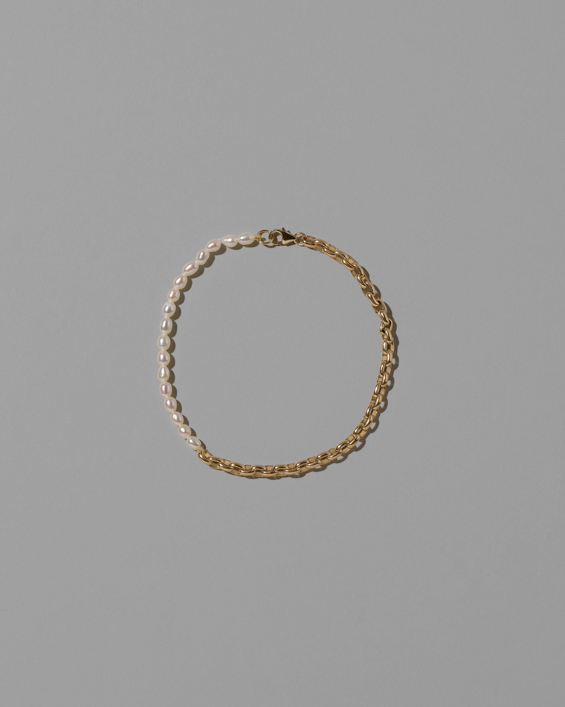 Half Short Loop Chain & White Seed Pearl Bracelet on light color background.