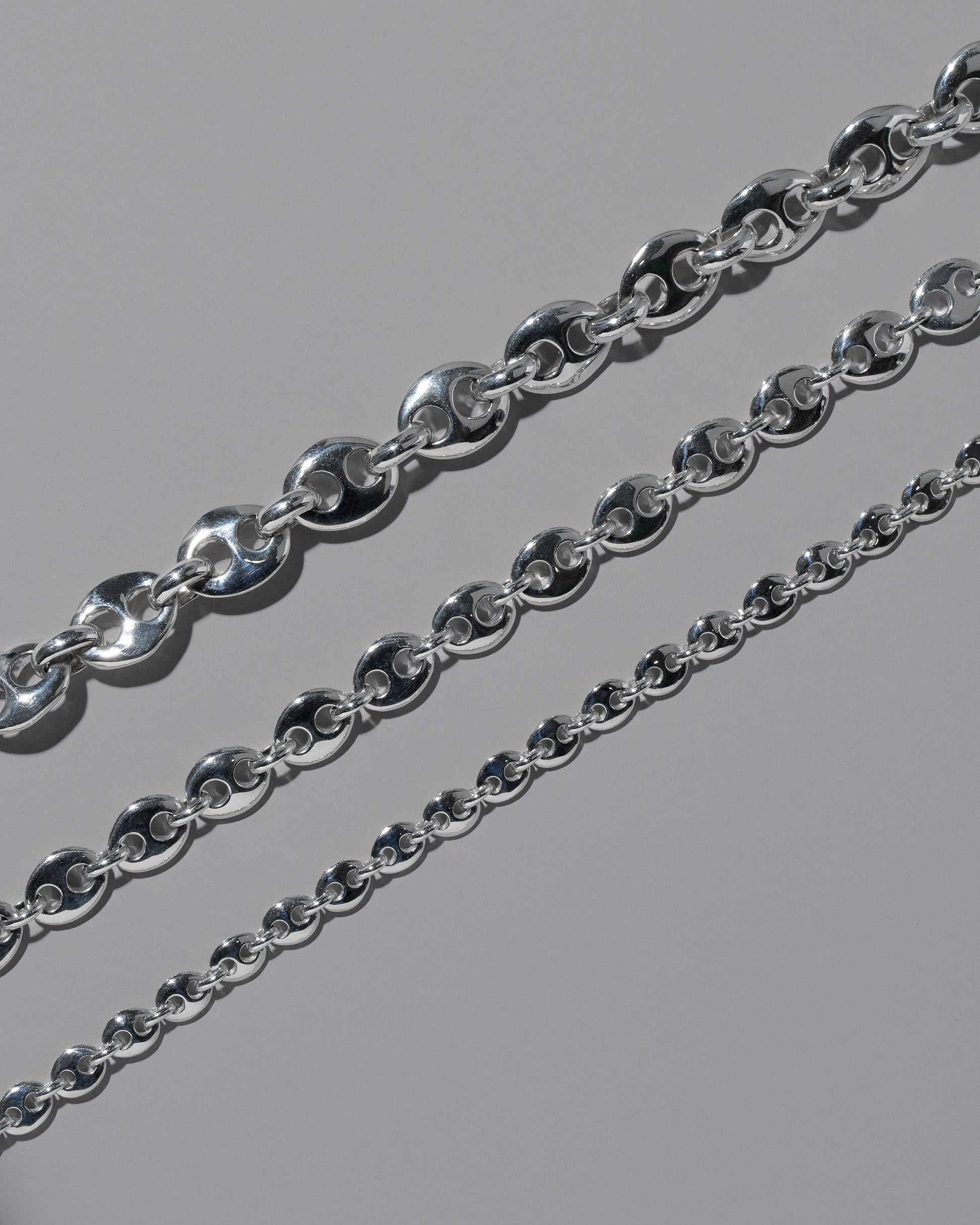 Closeup details of the CRZM Sterling Silver Bedrock Mini Bracelet, Sterling Silver Bedrock Medium Bracelet, and Sterling Silver Bedrock Bracelet on light color background.