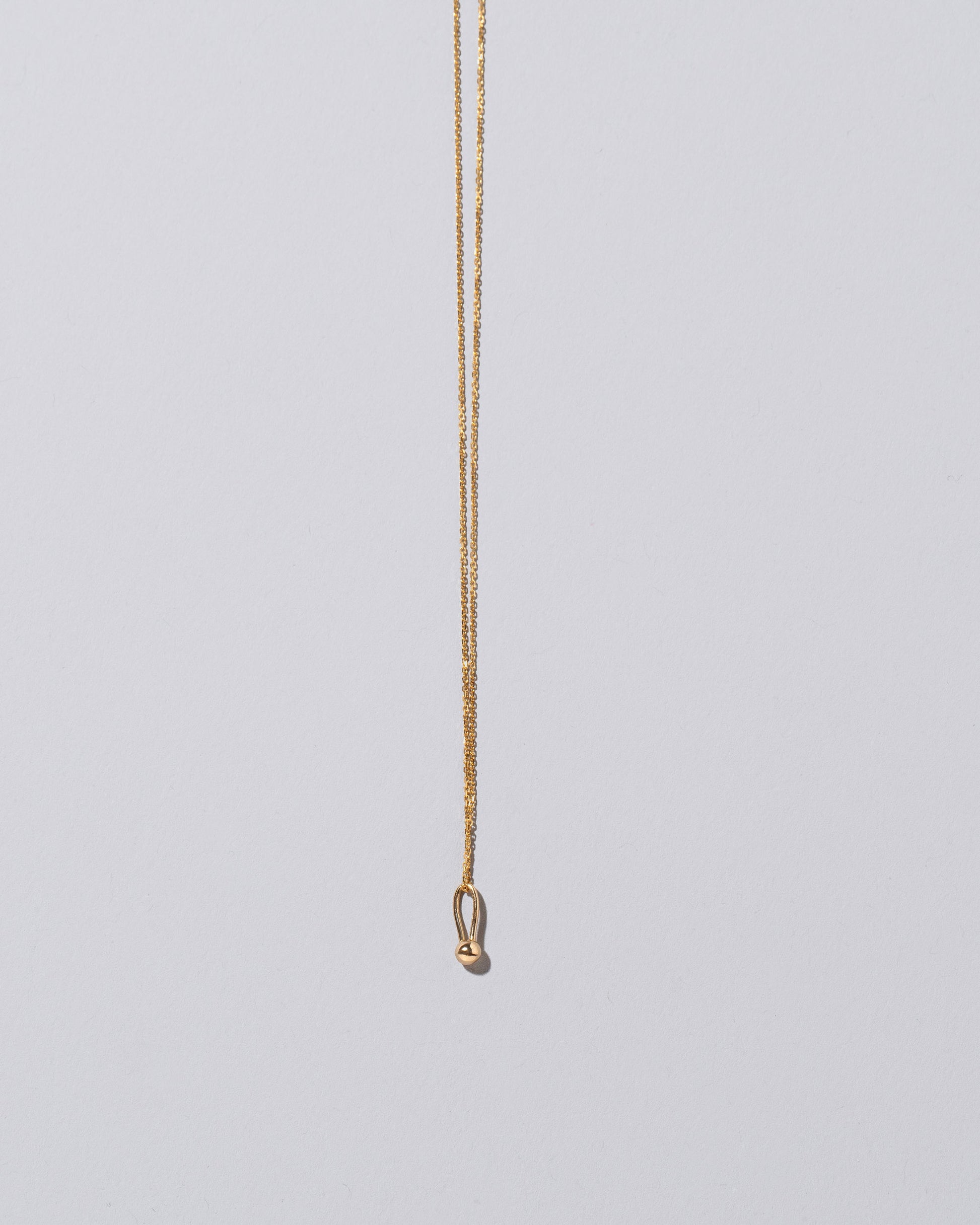 Loop & Sphere Talisman Pendant Necklace on light color background.