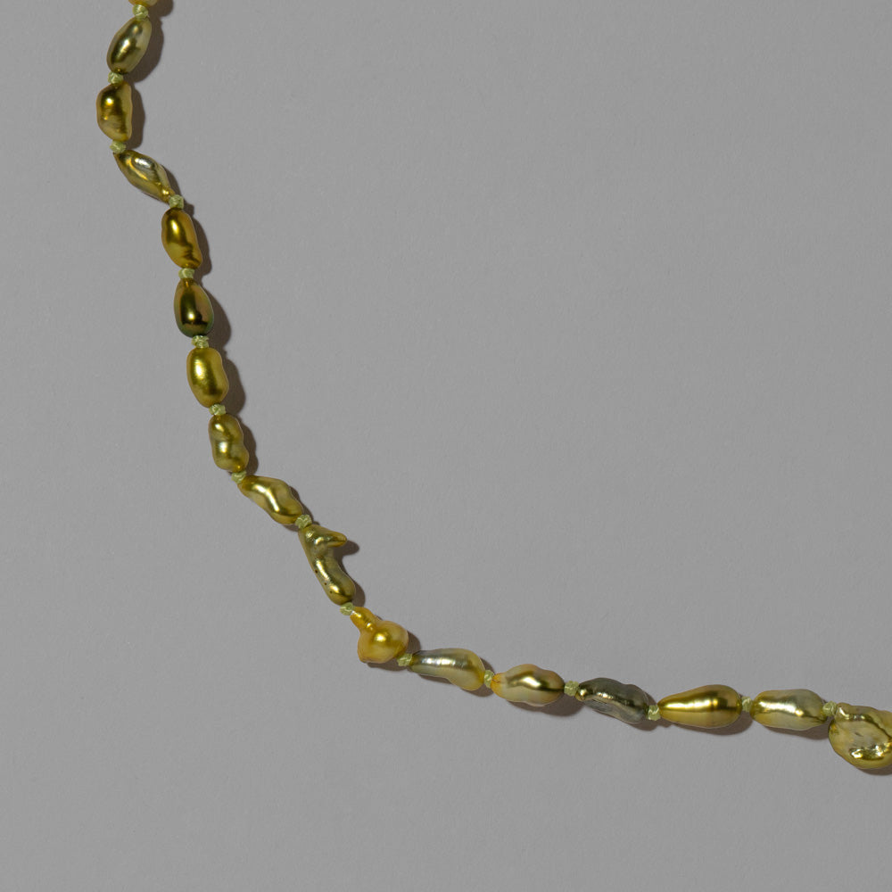 product_details::Closeup details of the Karkinos Necklace on light color background.