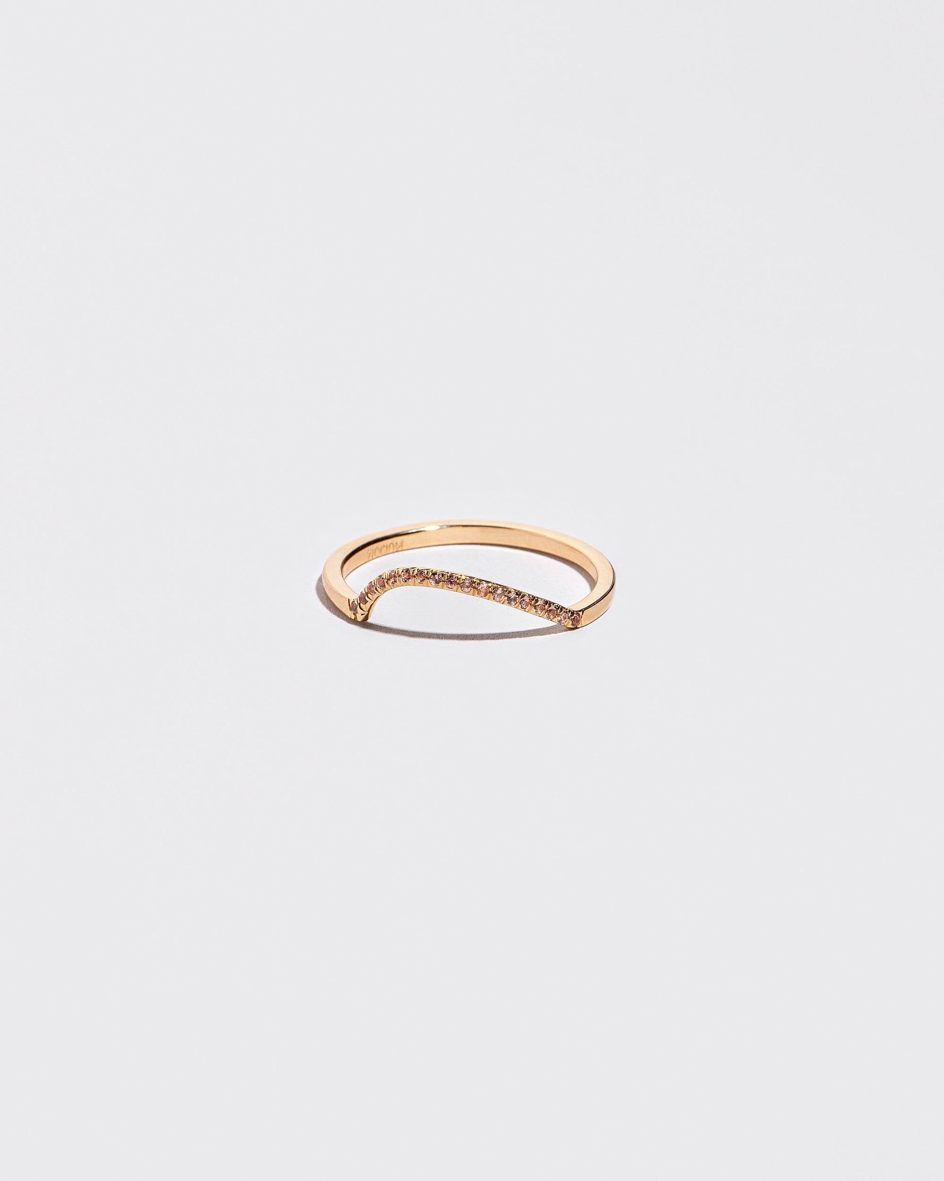Gold Pavé Peach Sapphire Left Slump Band on light color background.